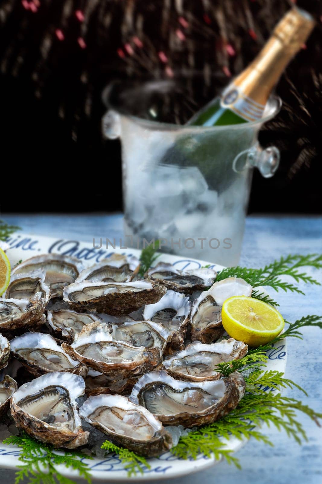 A dish with oysters on a table with festive decor and champagne botle. Christmas celebration. Close-up. by JPC-PROD