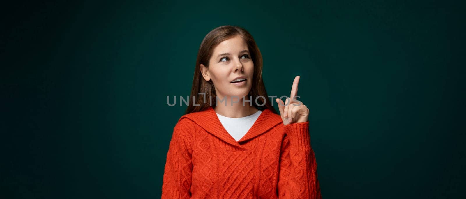 Portrait of a smart young woman in a red sweater who is thinking about something and looking up.