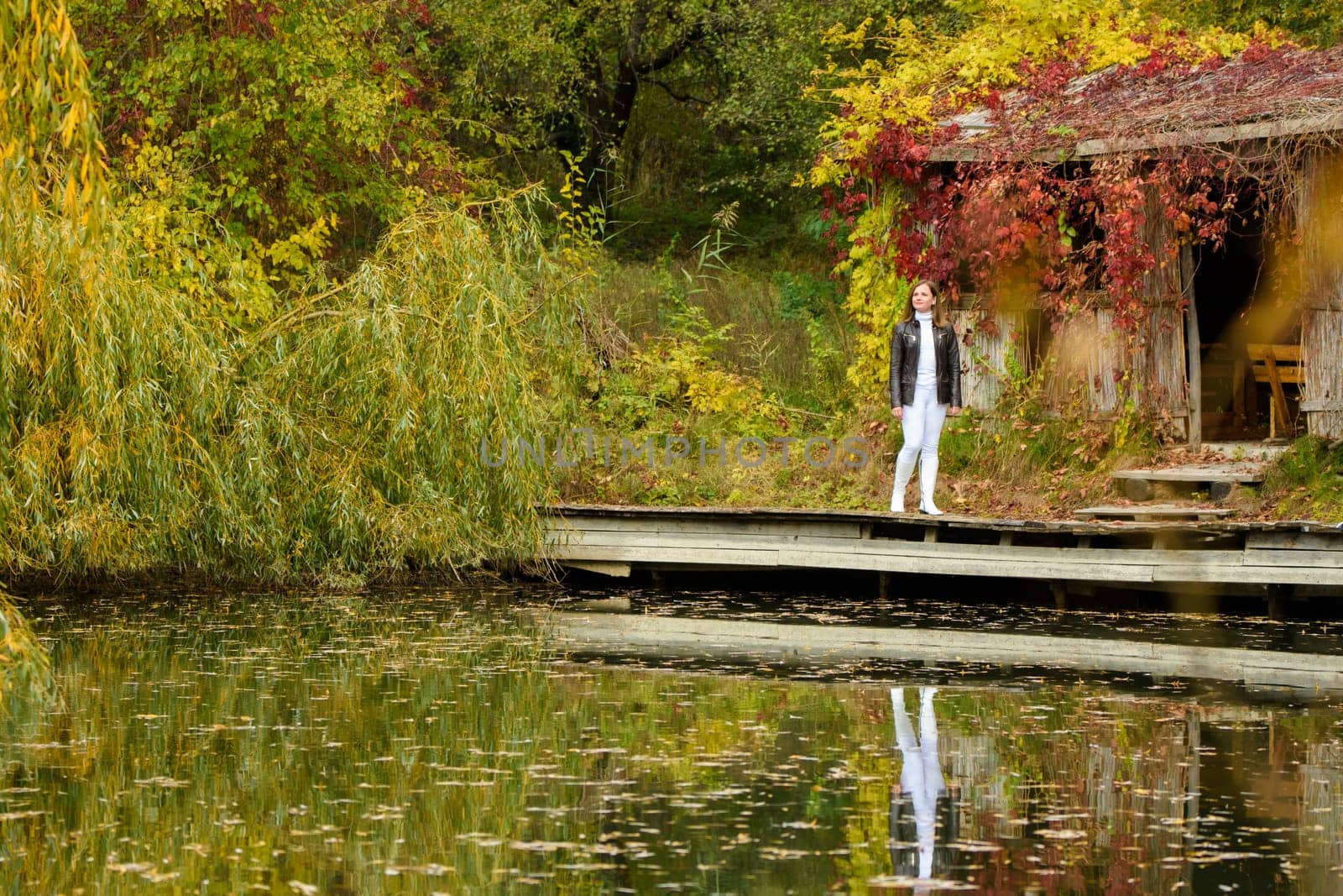 A young beautiful girl walks by the lake in an autumn park a