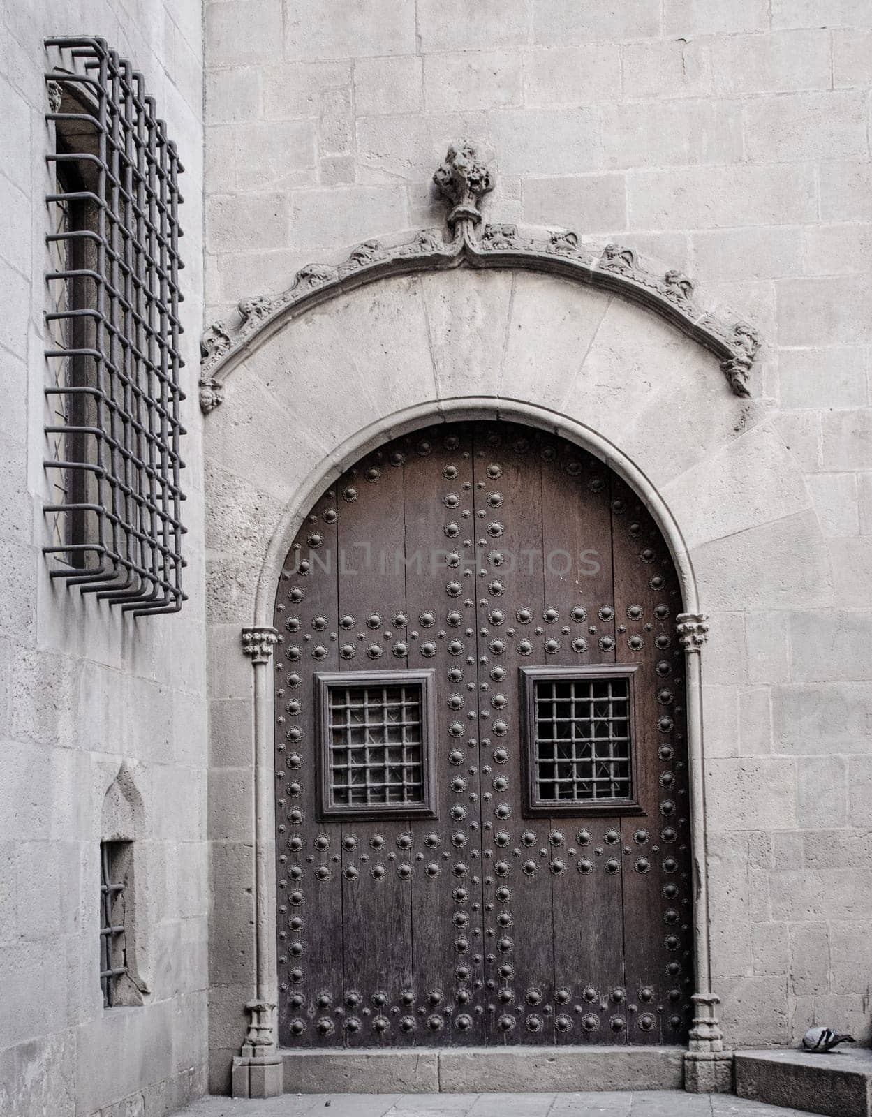 Wooden door with iron fittings in Gothic Quarter street in Catalonia. A medieval door of wood in a stone wall. by _Nataly_Nati_