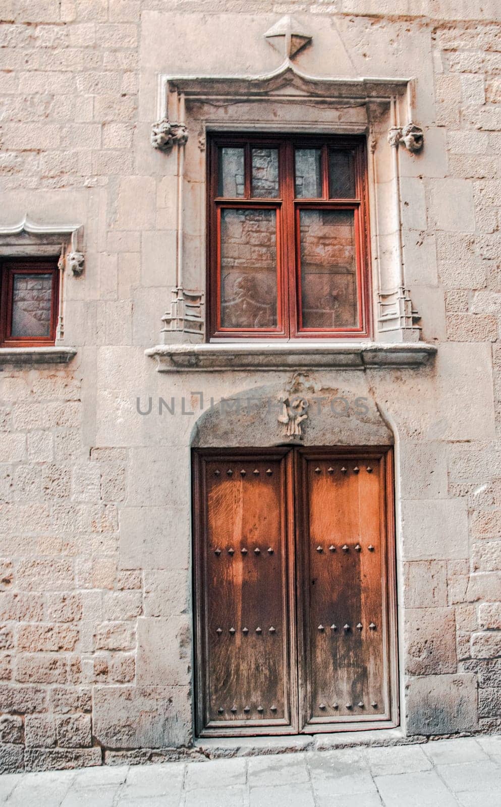 A medieval door of wood in a stone wall. Wooden door with iron fittings in Gothic Quarter street in Catalonia. Typical architecture of medieval Europe. High quality picture for wallpaper, article