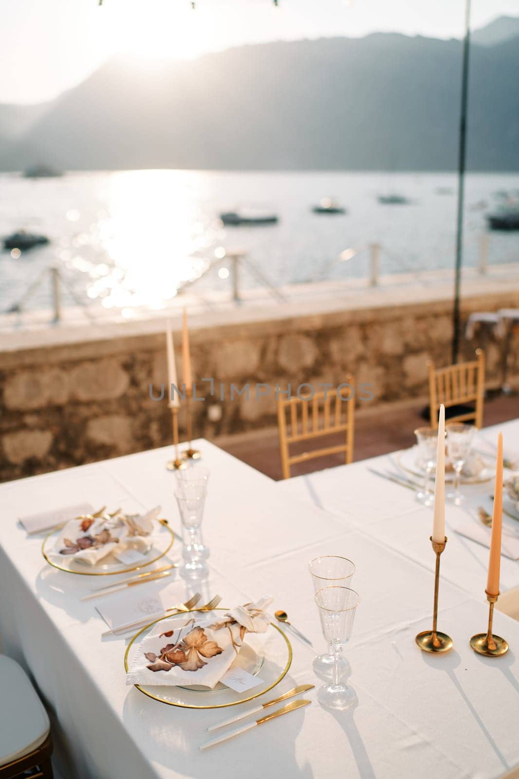 Bride and groom festive table with candles and menu stands on the terrace by the sea. High quality photo