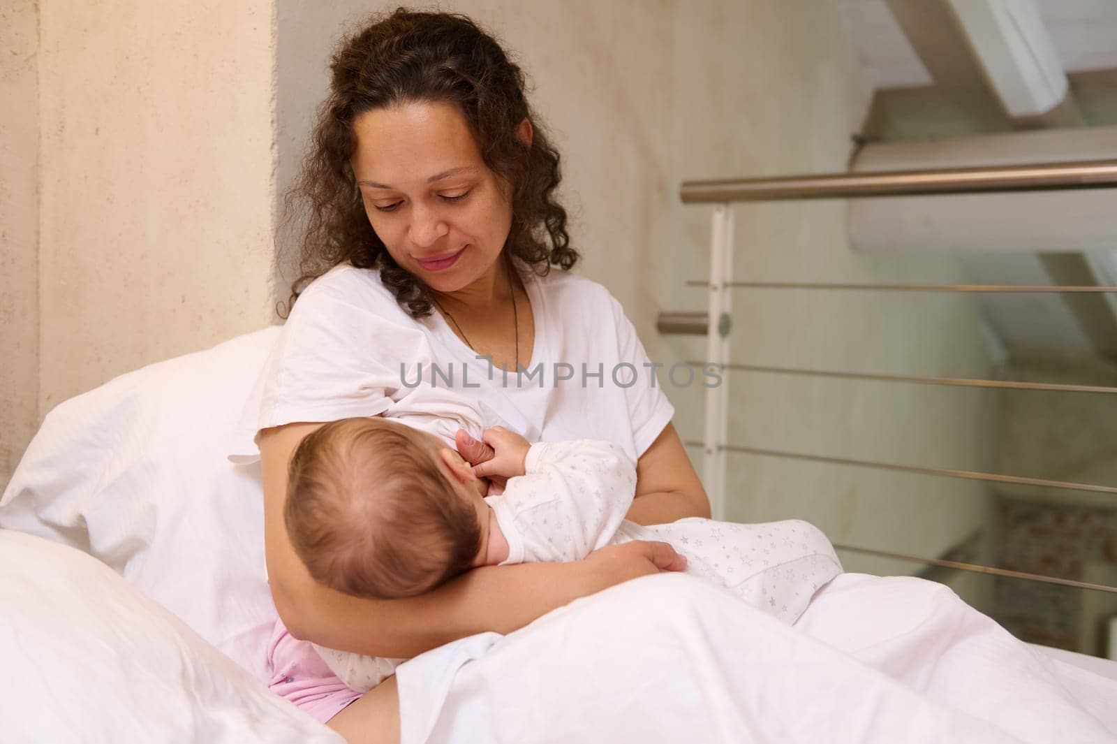 Beautiful loving Latin American mother breastfeeding her baby. Maternity leave and infancy concept. Copy advertising space