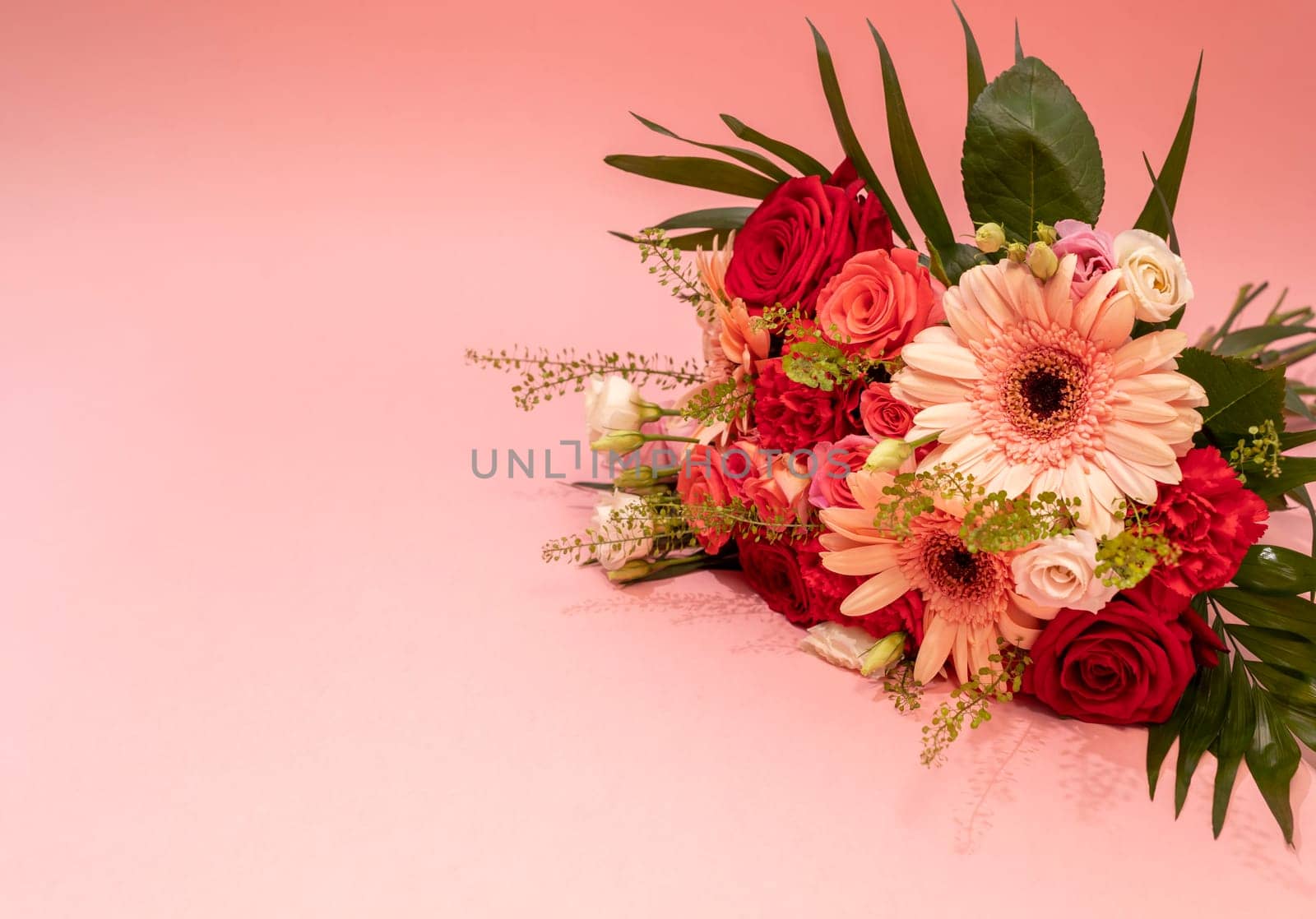 Mockup Beautiful Fresh Bouquet Of Flowers On Pinsk Background. Colorful Mixed Roses, Carnation Shabot, Green Leaves, Gerber. Horizontal Plane, Copy Space For Text by netatsi