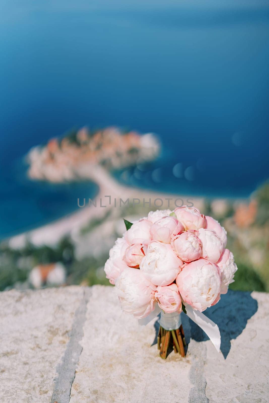 Wedding bouquet stands on a stone fence on a mountain above the sea by Nadtochiy