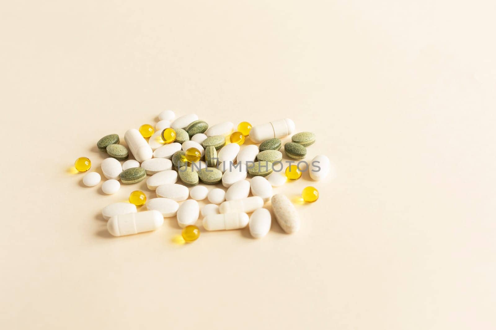 Assorted Pile of Colorful Pills, Green White Yellow, Beige Tablets, Capsules, Medical Supplement on Beige Background. Pharmaceutical concept. Copy Space For Text. Horizontal Plane. High quality photo