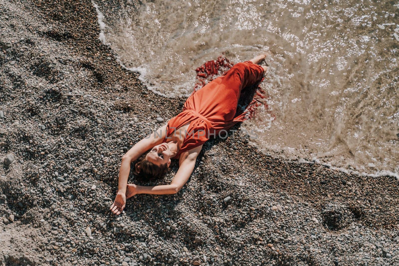 Woman red dress sea. Female dancer in a long red dress posing on a beach with rocks on sunny day by Matiunina