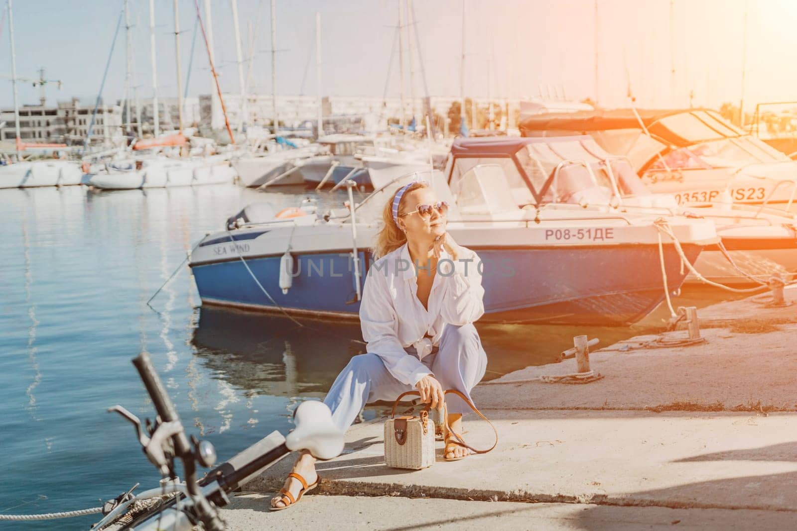 Woman in white shirt in marina , surrounded by several other boats. The marina is filled with boats of various sizes, creating a lively and picturesque atmosphere. by Matiunina