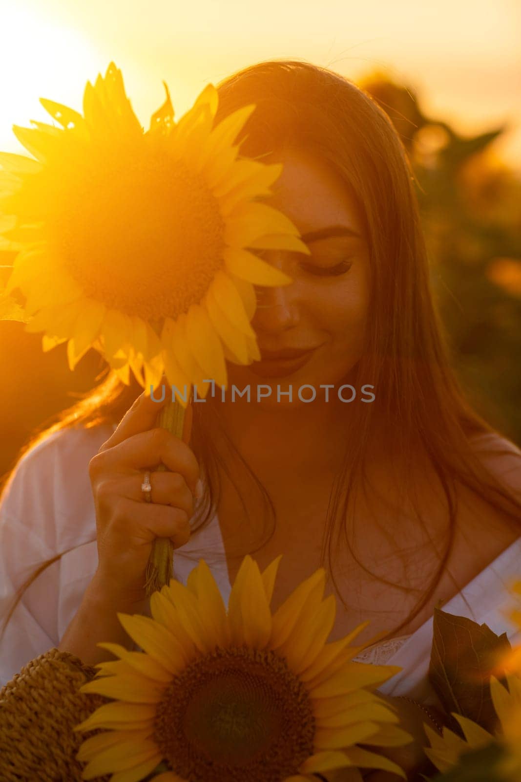 A girl in a hat on a beautiful field of sunflowers against the s by Matiunina