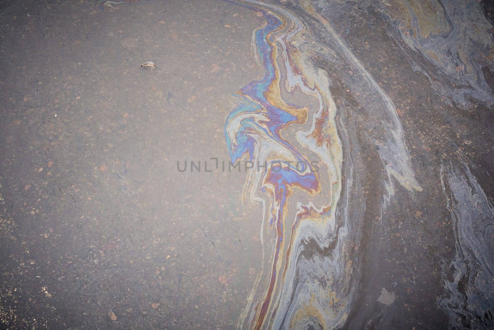 Dirty multi-colored stain from engine oil on asphalt. Environmental pollution concept.