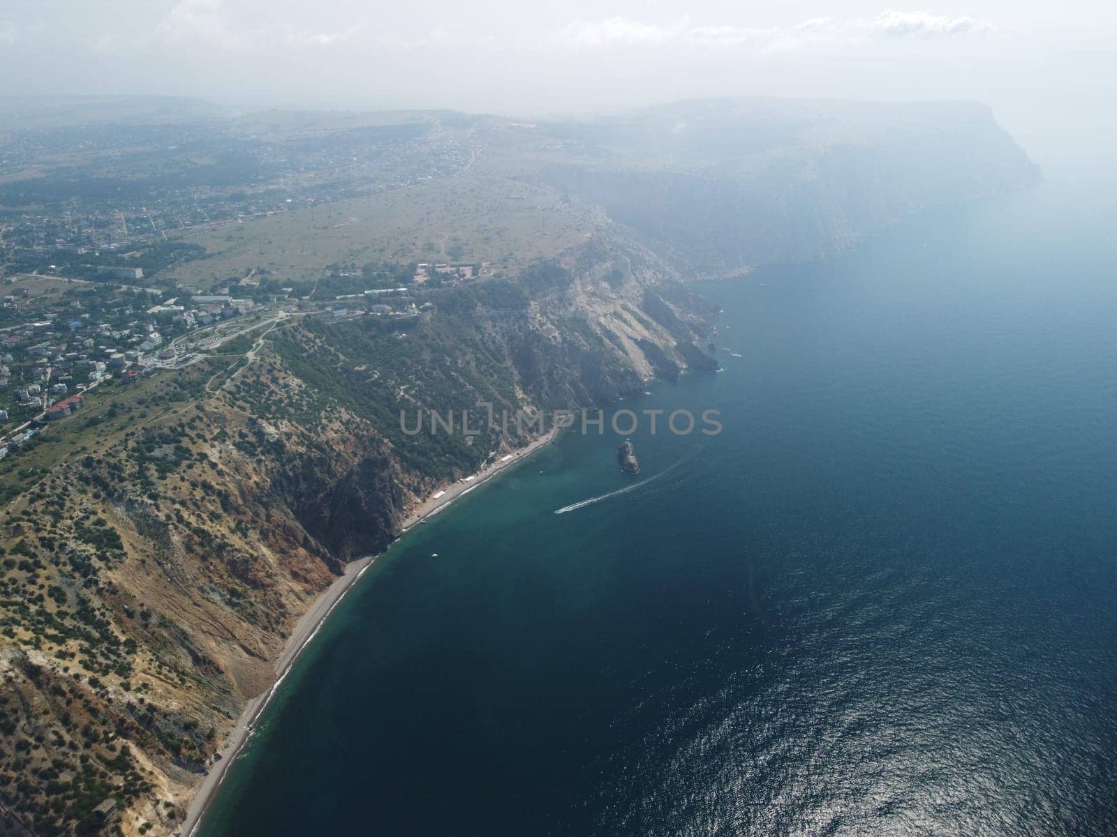 Aerial view from above on calm azure sea and volcanic rocky shores. Small waves on water surface in motion blur. Nature summer ocean sea beach background. Nobody. Holiday, vacation and travel concept by panophotograph