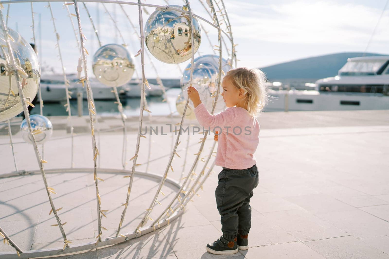 Little girl stands near a spherical Christmas installation with mirror balls. High quality photo