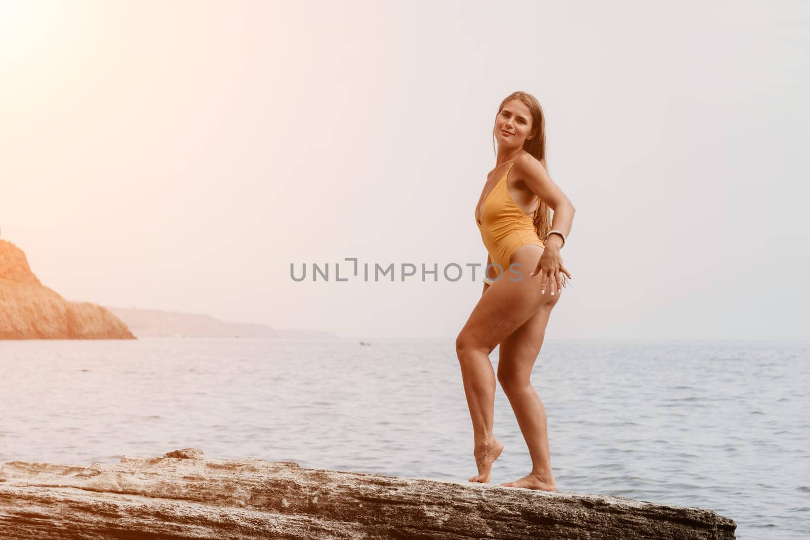 Woman meditating in yoga pose silhouette at the ocean, beach and rock mountains. Motivation and inspirational fit and exercising. Healthy lifestyle outdoors in nature, fitness concept.