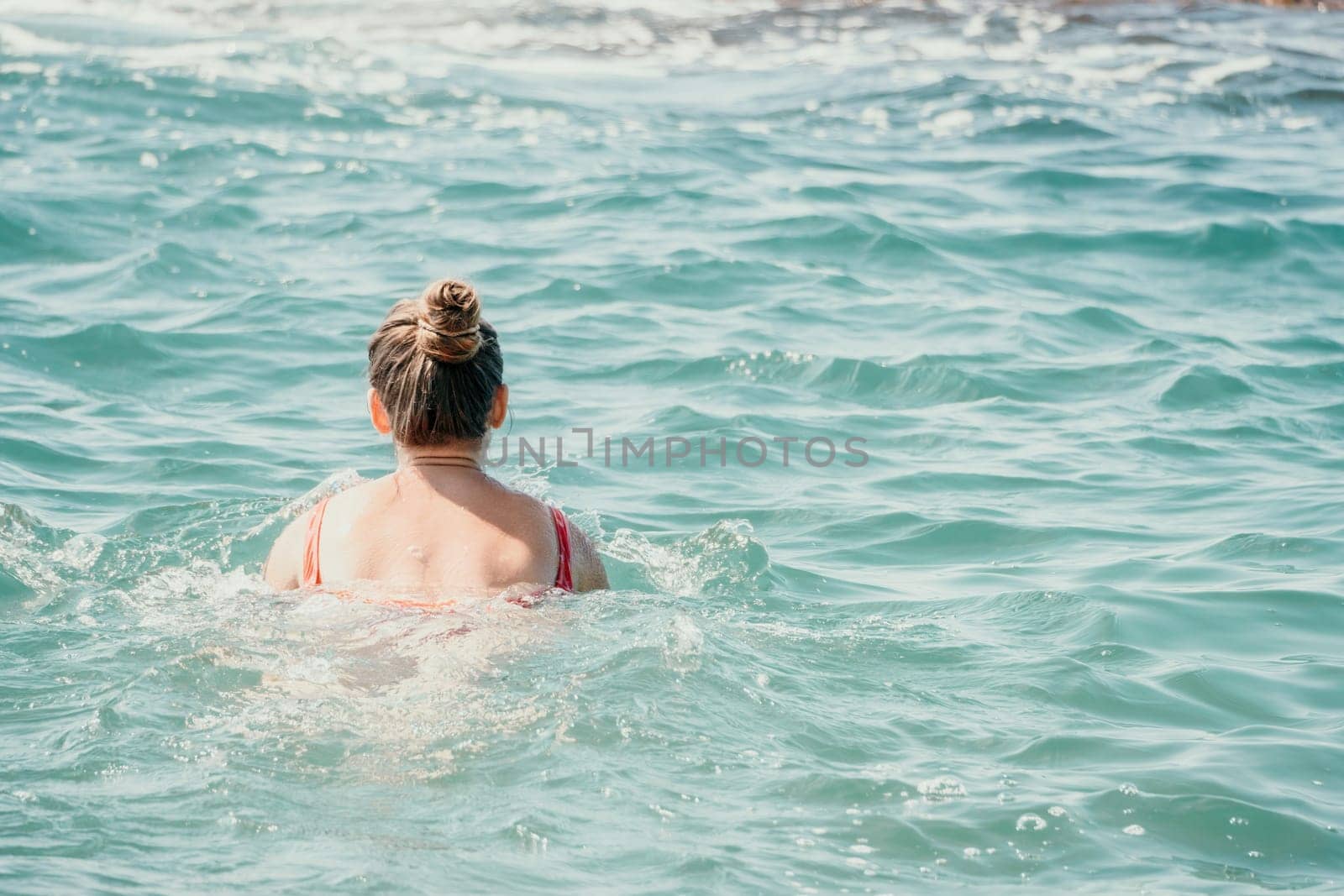 Young woman in red bikini on Beach. Happy lady in bathing suit chilling and sunbathing by turquoise sea ocean on hot summer day. Close up. Back view by panophotograph