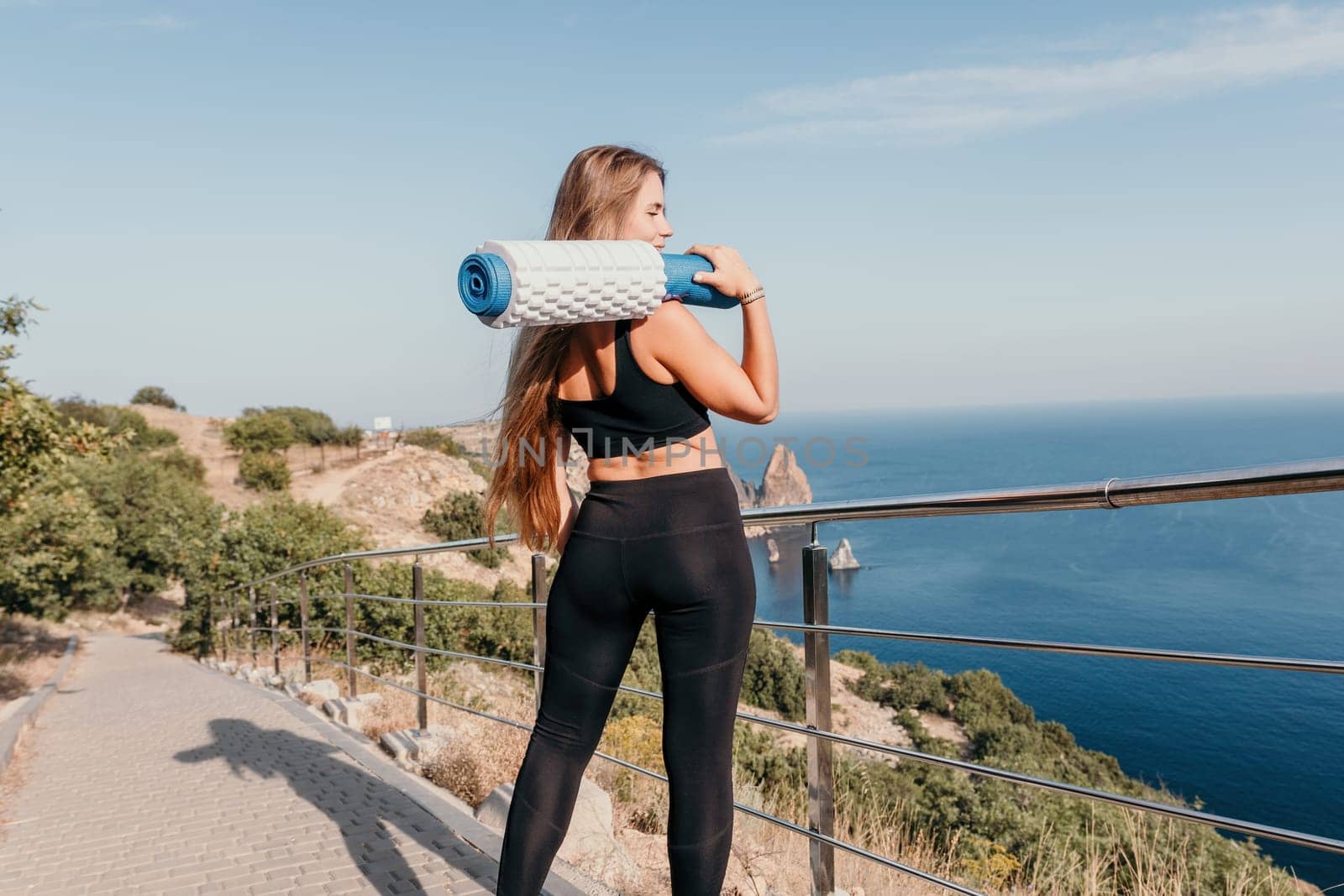 Fitness woman sea. Outdoor workout on yoga mat in park near to ocean beach. Female fitness pilates yoga routine concept. Healthy lifestyle. Happy fit woman exercising with rubber band in park.