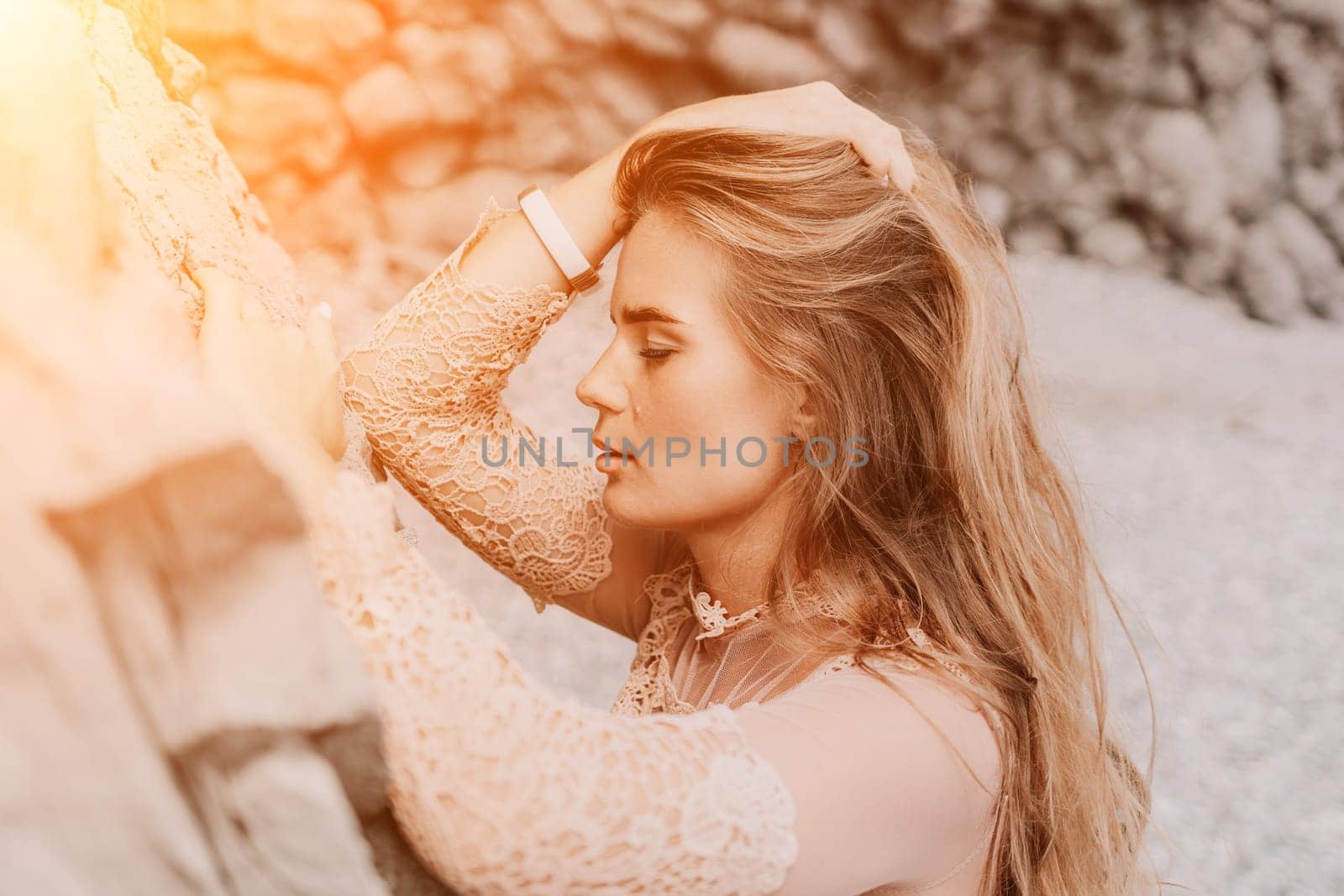 Woman summer travel sea. Happy tourist in beige dress enjoy taking picture outdoors for memories. Woman traveler posing on the beach surrounded by volcanic mountains, sharing travel adventure journey by panophotograph