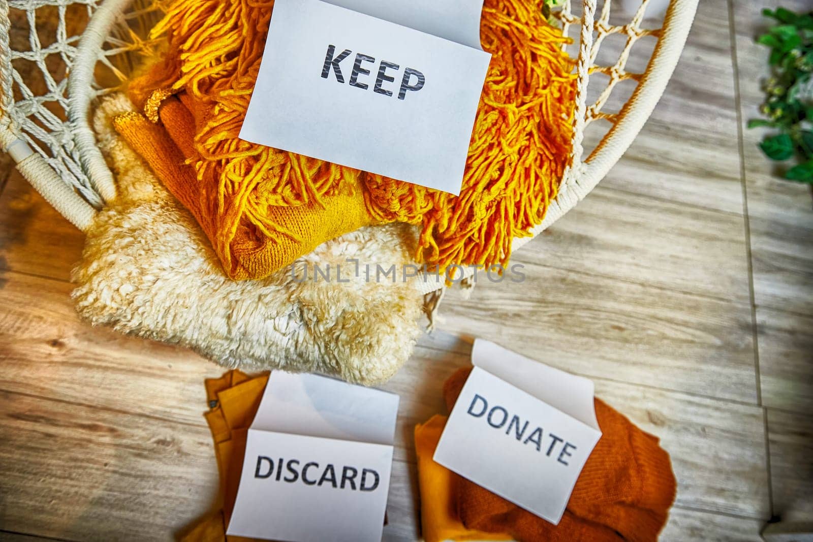 Signs with the words keep, donate, discard and fashion clothes folded in stacks in cozy room. The concept of cluttering and decluttering. Background