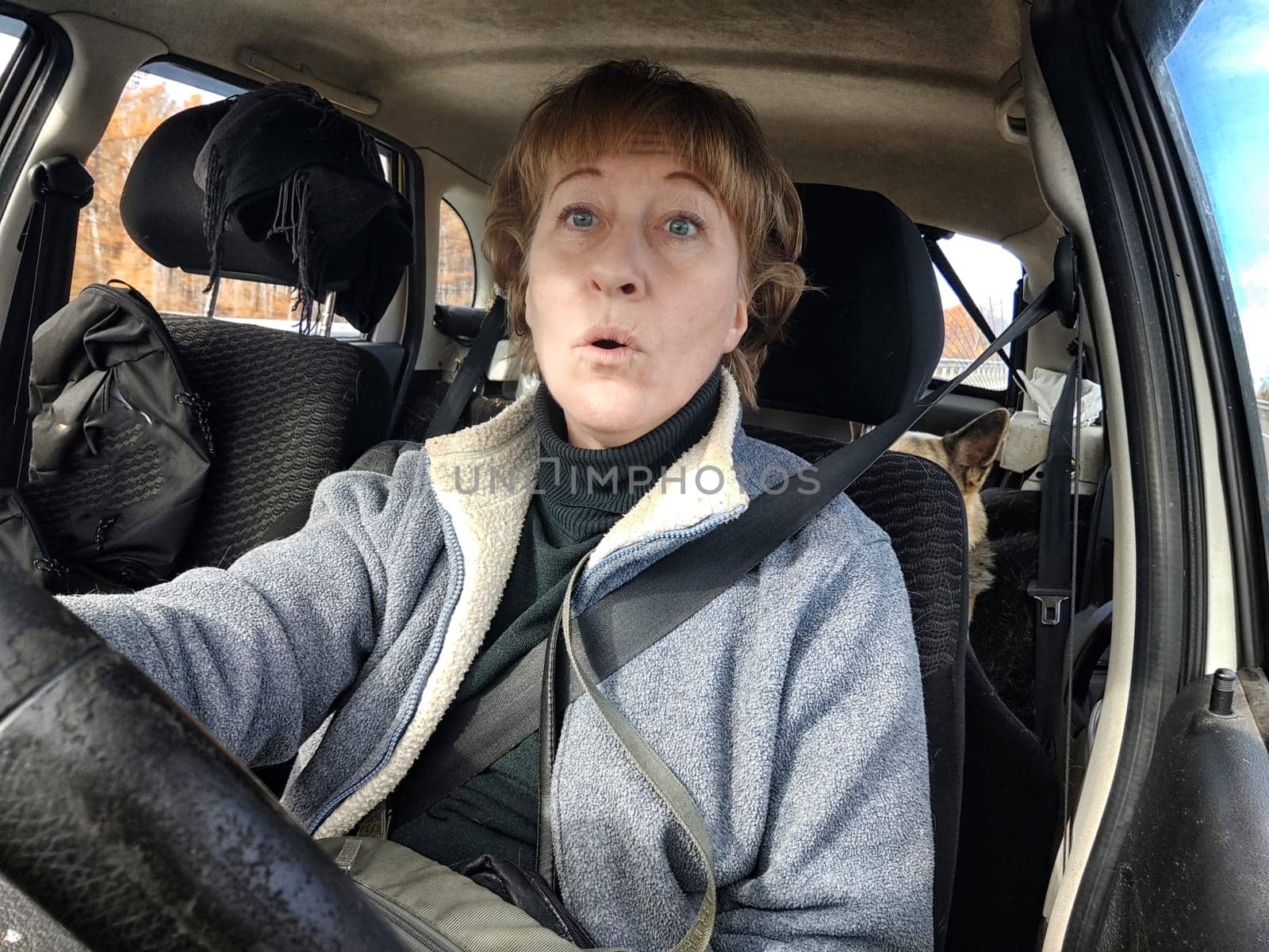 Terrified female driver a second before the accident. Scared middle-aged adult woman holds the steering wheel of a car. Frightened Lady girl who is owner or rent a car for travel by keleny