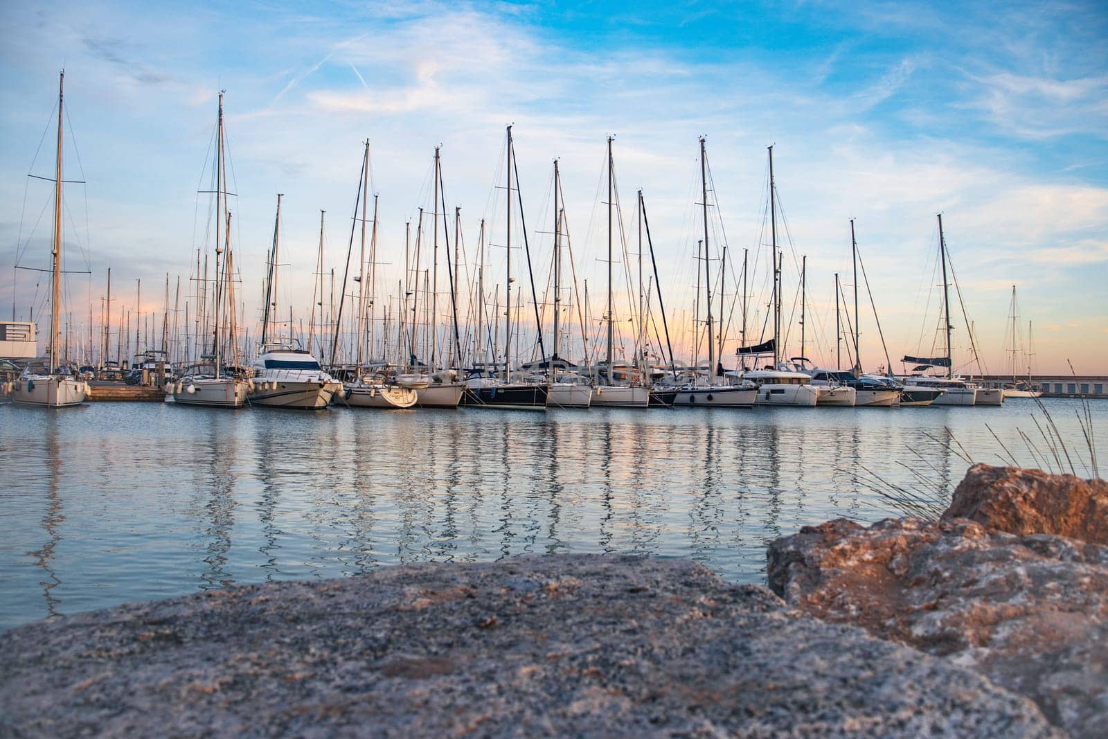 Sailboat harbor in the port evening photo. Beautiful moored sail yachts in the sea, modern water transport Barcelona, Catalonia. Bright sunset and dusk. High quality picture for wallpaper, article