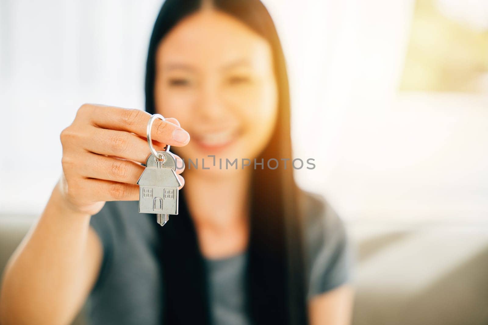 A woman's hand holds house key highlighting homeowners' achievement by Sorapop