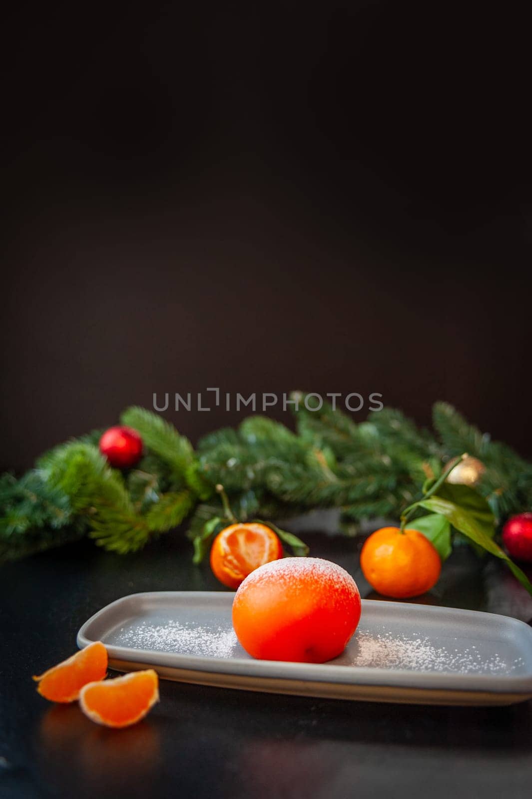 Plate with delicious mochi and tangerine on a dark Christmas background. High quality photo