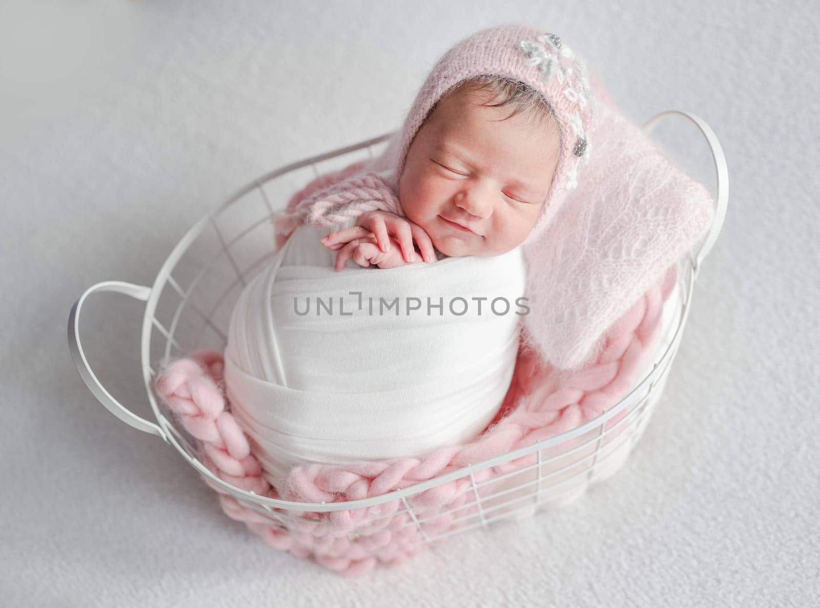 Newborn Girl Sleeps With A Smile In A Basket During A Baby Photo Session In The Studio