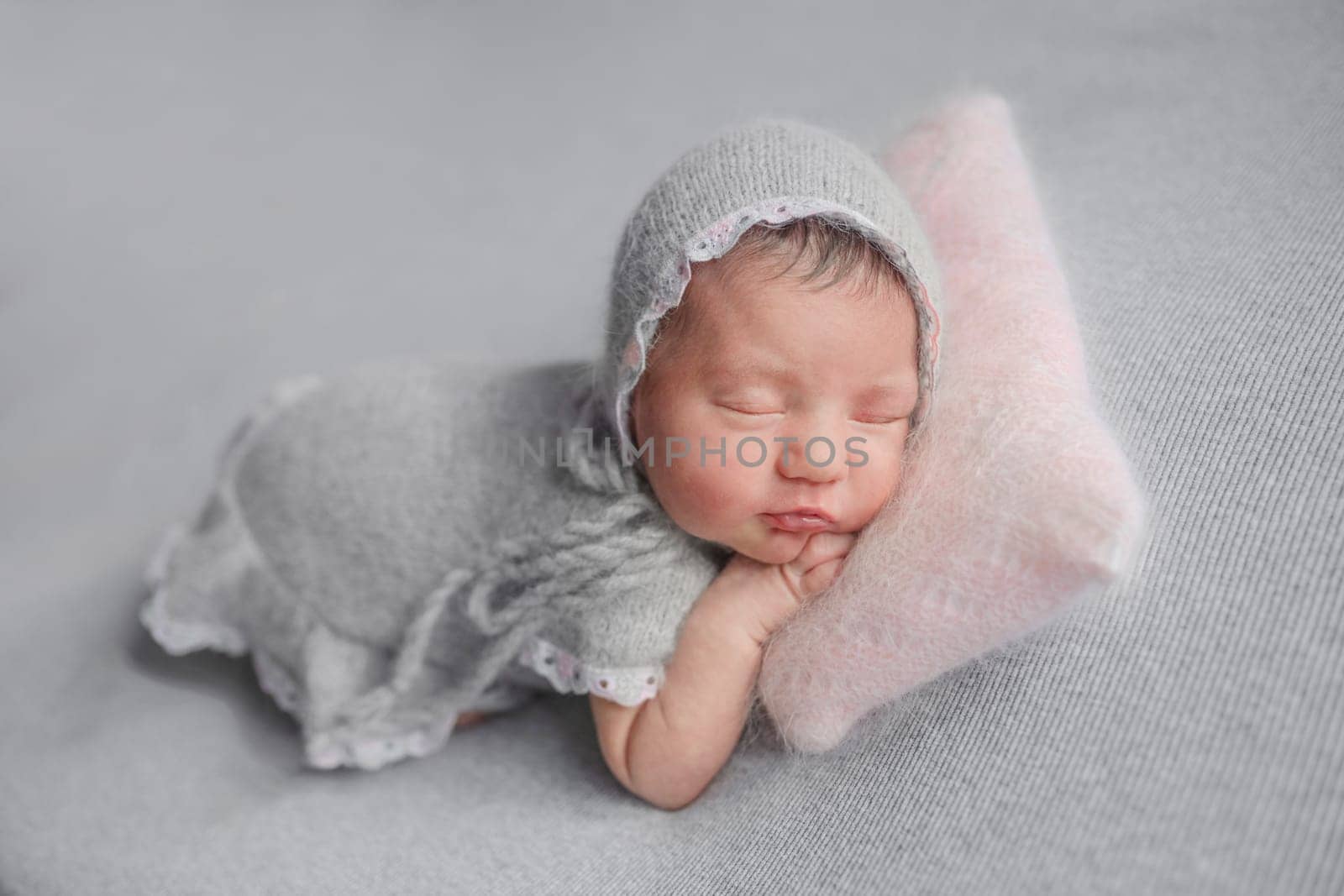 Newborn Girl Sleeps In Grey Dress During Baby Photoshoot In Studio