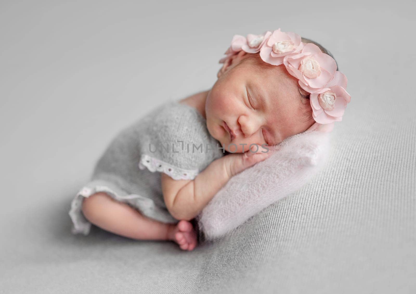 Newborn Girl Sleeps In Grey Dress During Baby Photoshoot In Studio