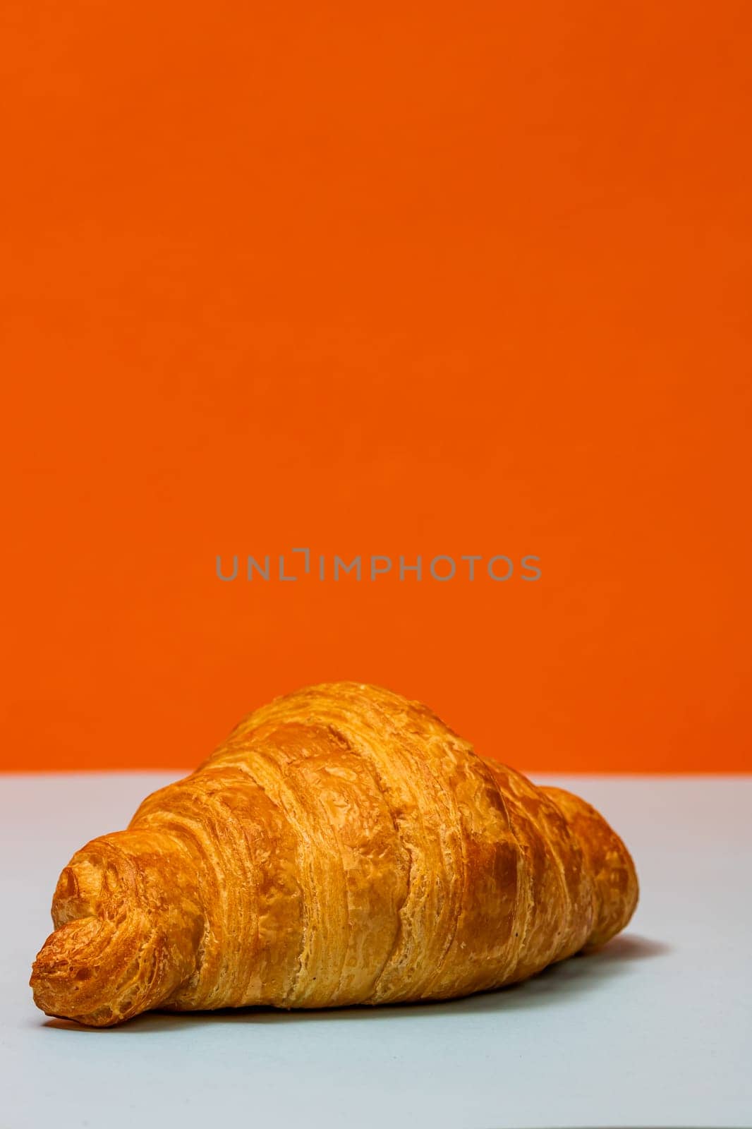  Fresh croissant isolated on orange board. French breakfast concept. by vladispas