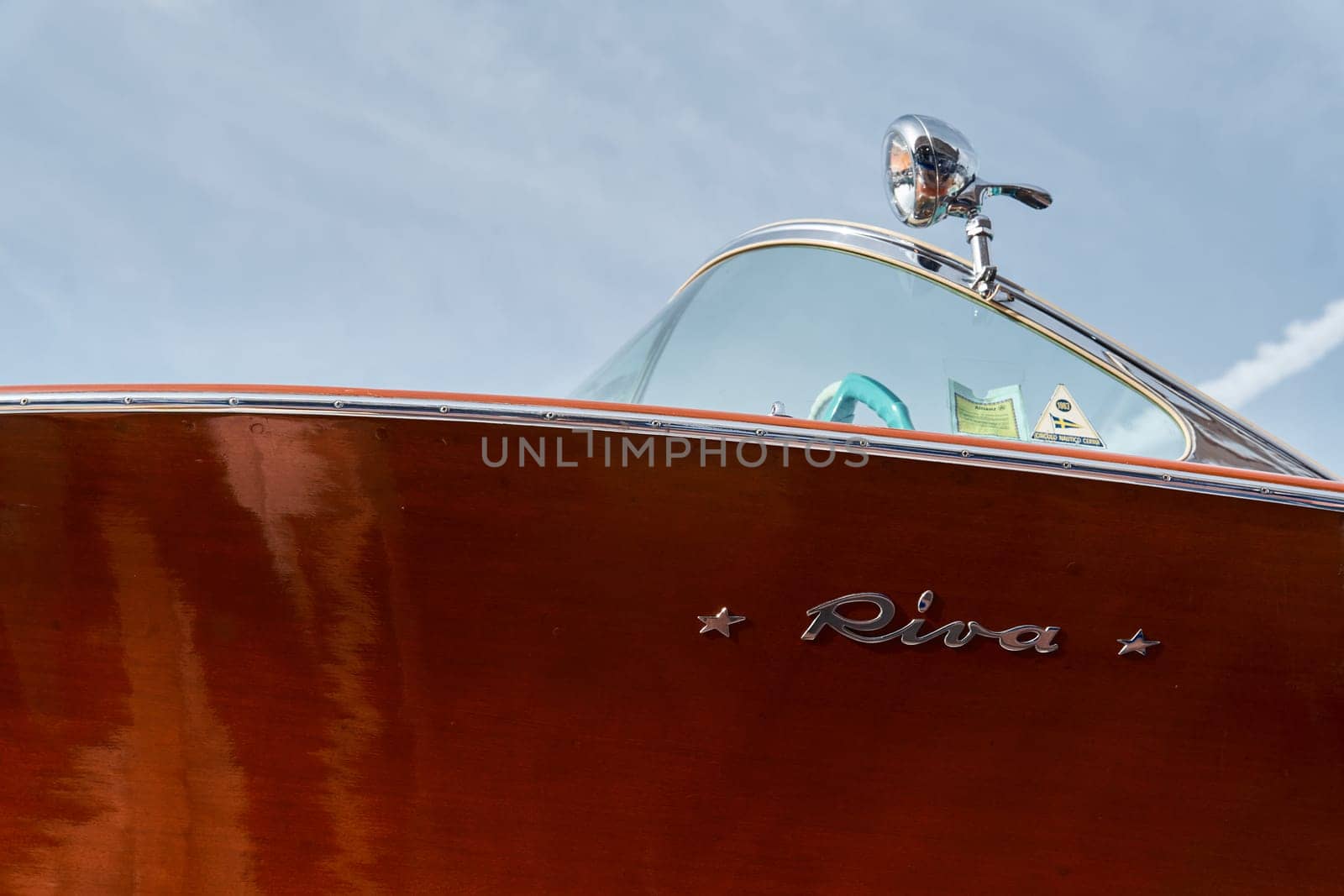Monaco, Monte Carlo, 29 September 2022 - the wooden side of the luxury motor boat Riva in port of Hercules, sunny glare of the sun, elegance boat, glossy surfaces shine in sunny weather. High quality photo