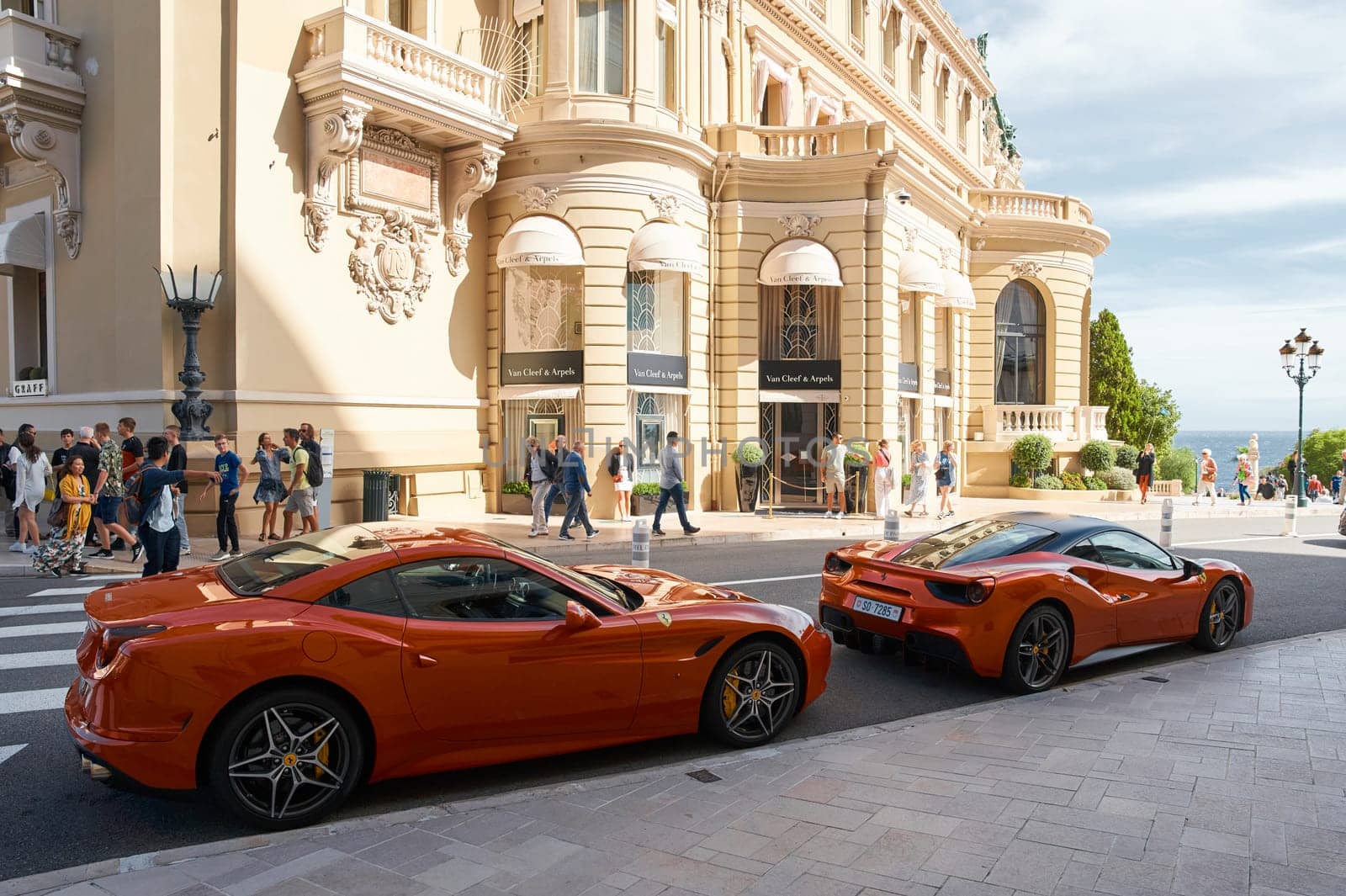 Monaco, Monte-Carlo, 29 September 2022 - Famous square Casino Monte-Carlo at sunny day, two Ferrari convertible, luxury cars, wealth life, tourists take pictures of the landmark. High quality photo