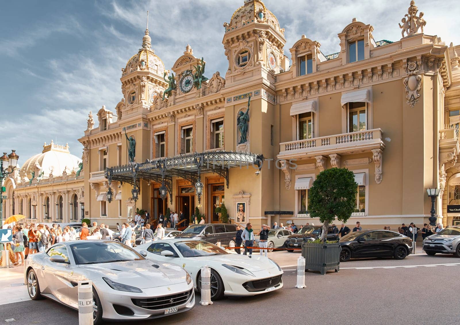 Monaco, Monte-Carlo, 29 September 2022 - Famous square Casino Monte-Carlo at sunny day, Ferrari convertible, luxury cars, wealth life, tourists take pictures of the landmark. High quality photo