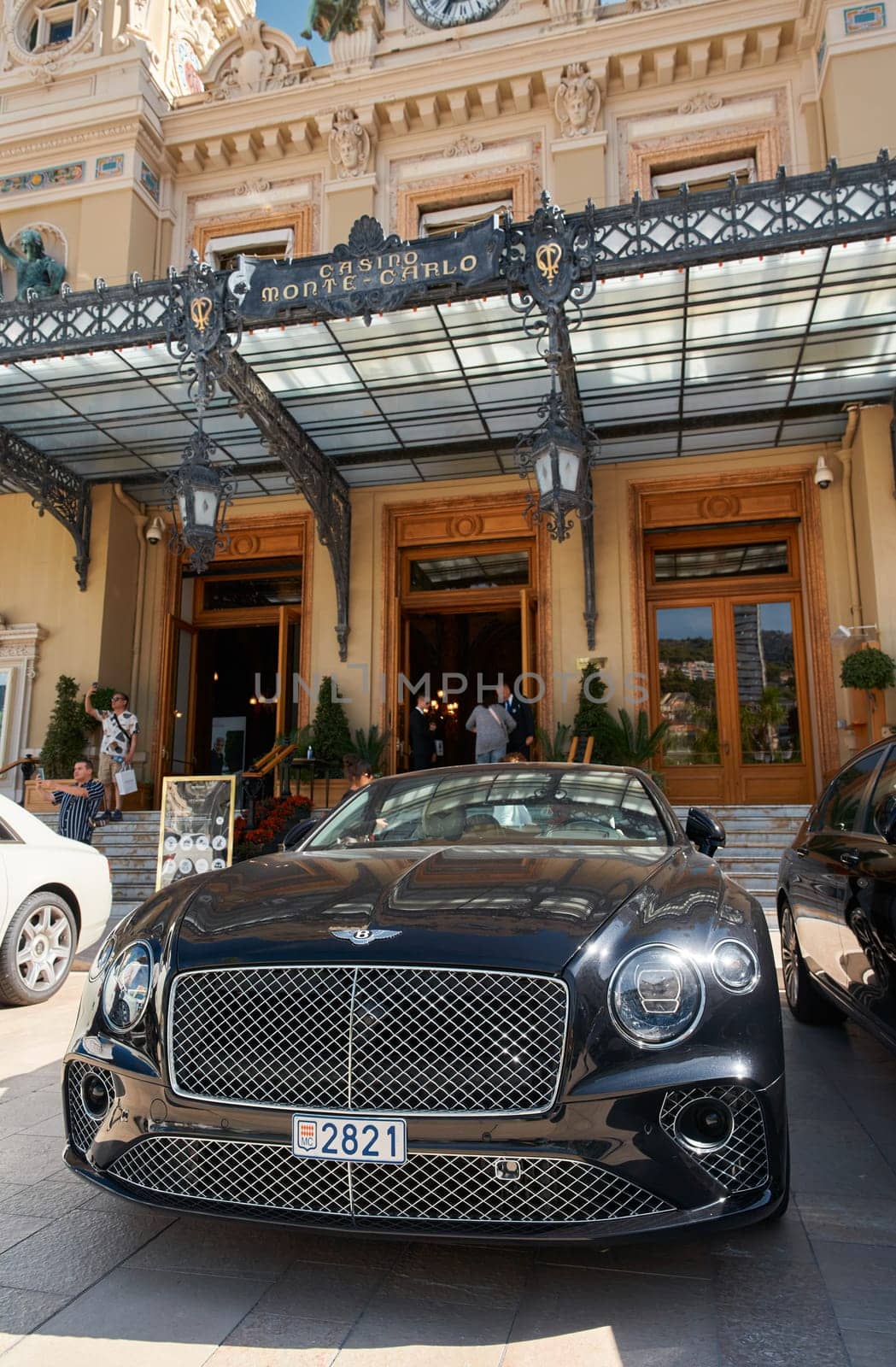 Monaco, Monte-Carlo, 29 September 2022 - Famous square Casino Monte-Carlo at sunny day, Bentley convertible, luxury cars, wealth life, tourists take pictures of the landmark. High quality photo