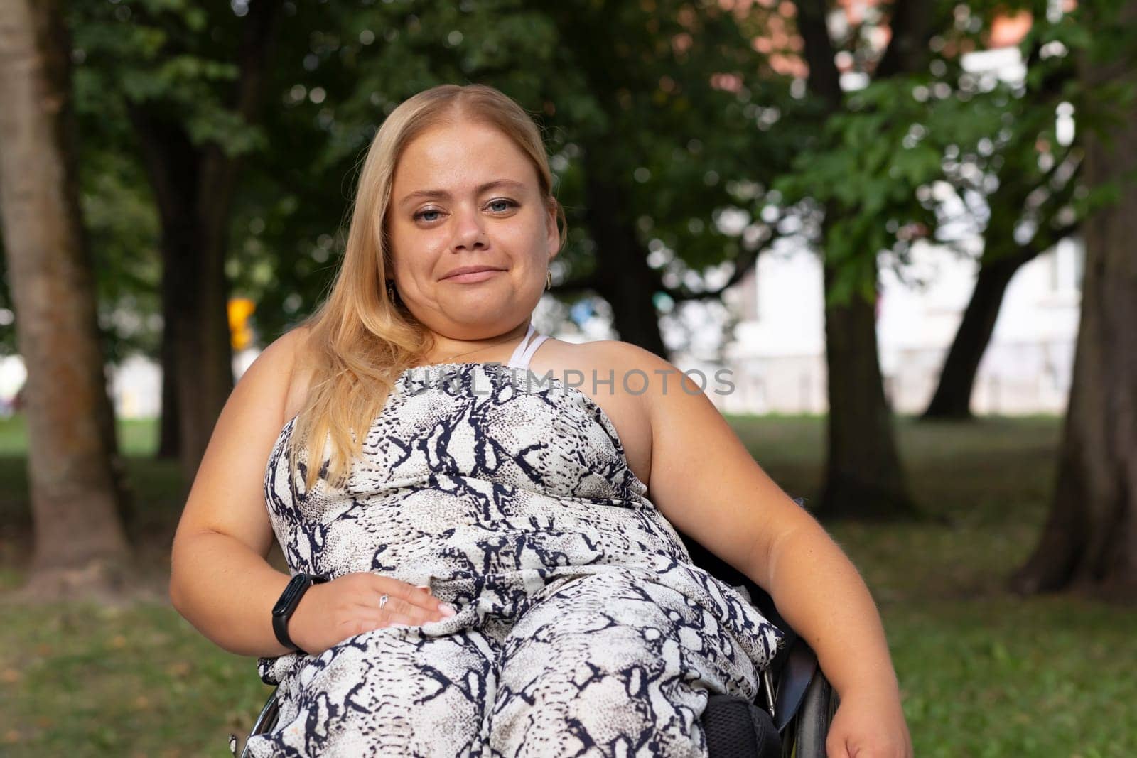 Smiling Brightly Young Woman With Short Stature Sitting In Wheel Chair In Green Park Outdoor. October Dwarfism Awareness Month. Horizontal. High quality photo