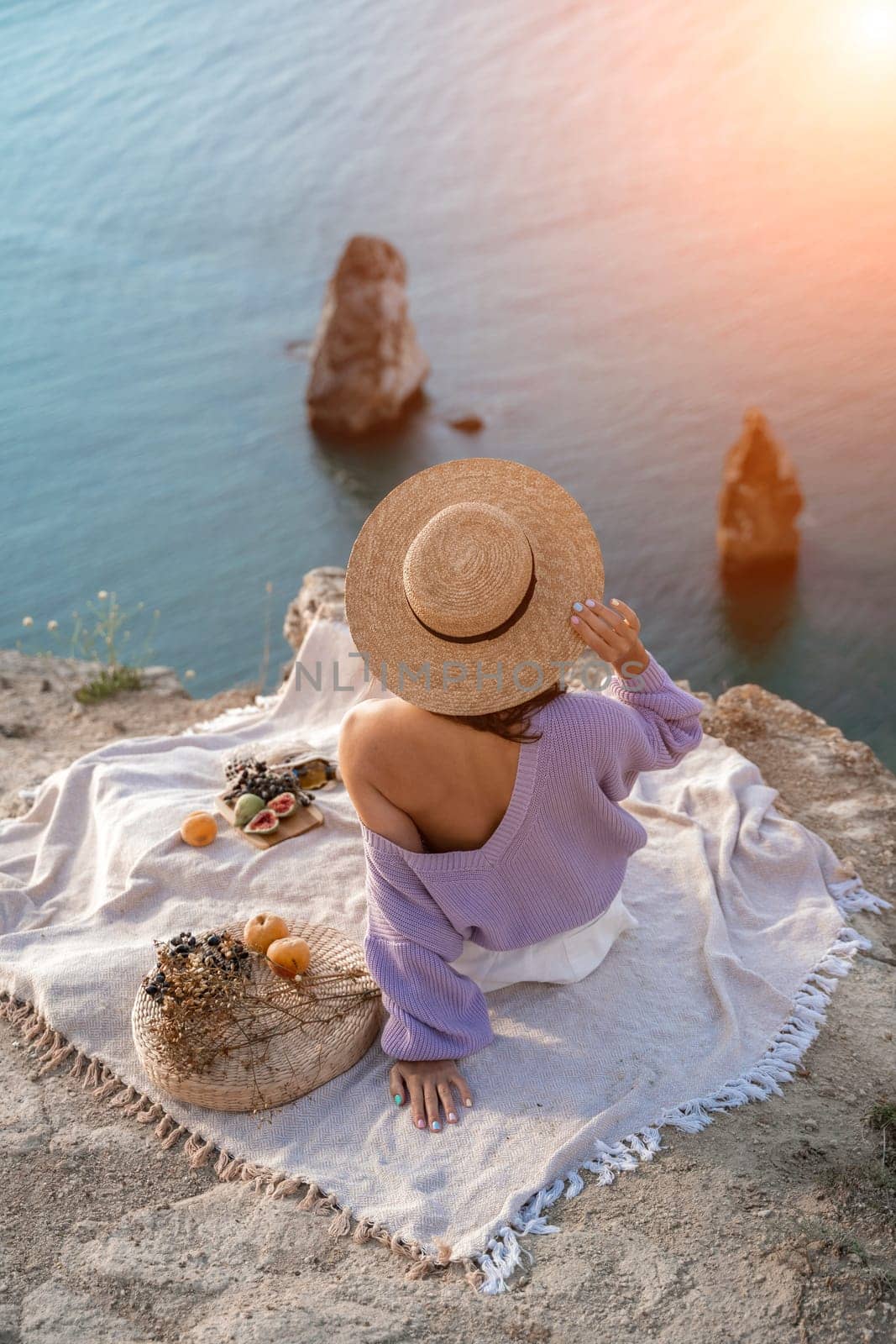 woman sea travel. photo of a beautiful woman with long blond hair in a pink shirt and denim shorts and a hat having a picnic on a hill overlooking the sea by Matiunina