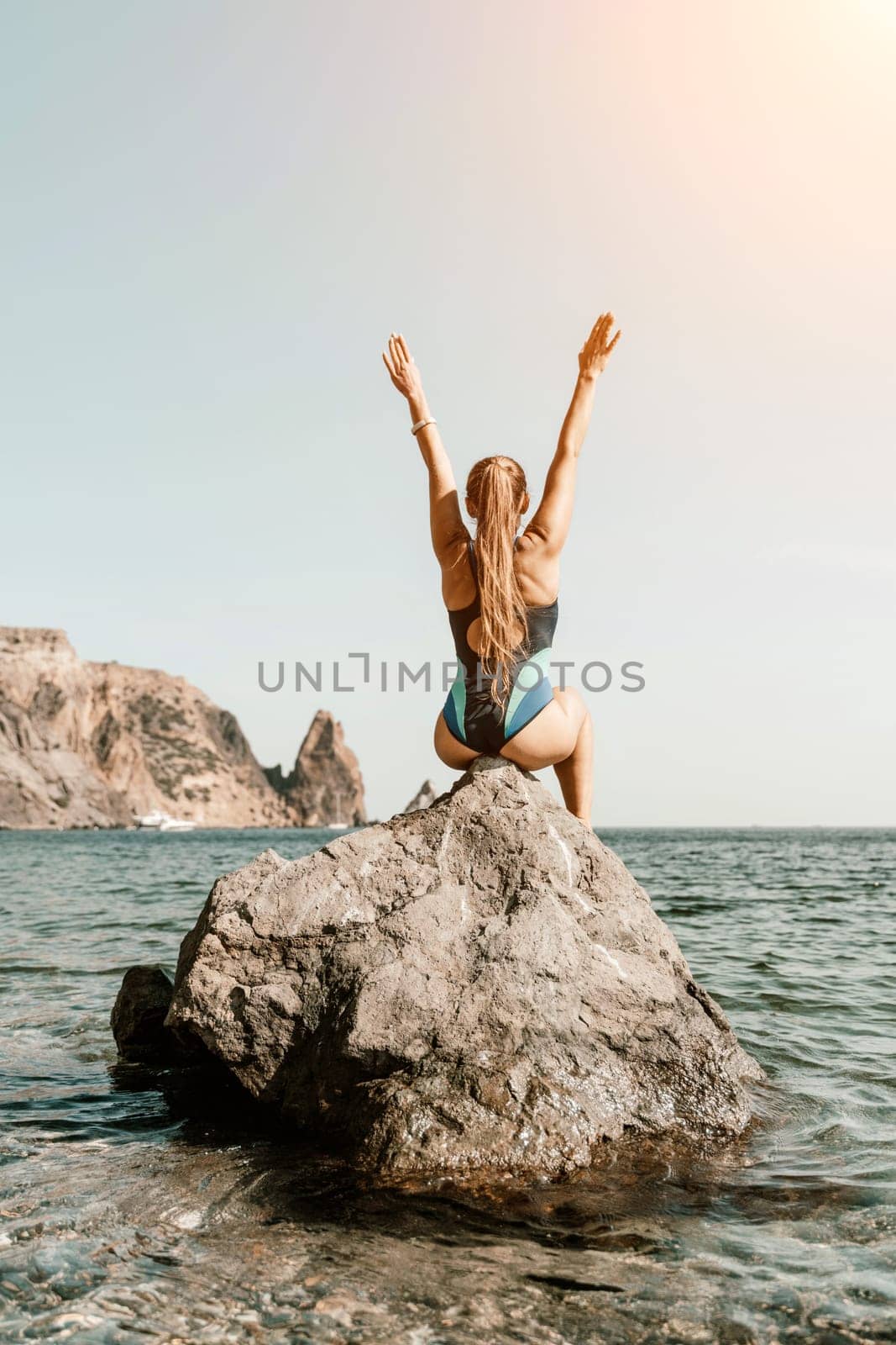 Woman travel summer sea. A happy tourist in a blue bikini enjoying the scenic view of the sea and volcanic mountains while taking pictures to capture the memories of her travel adventure