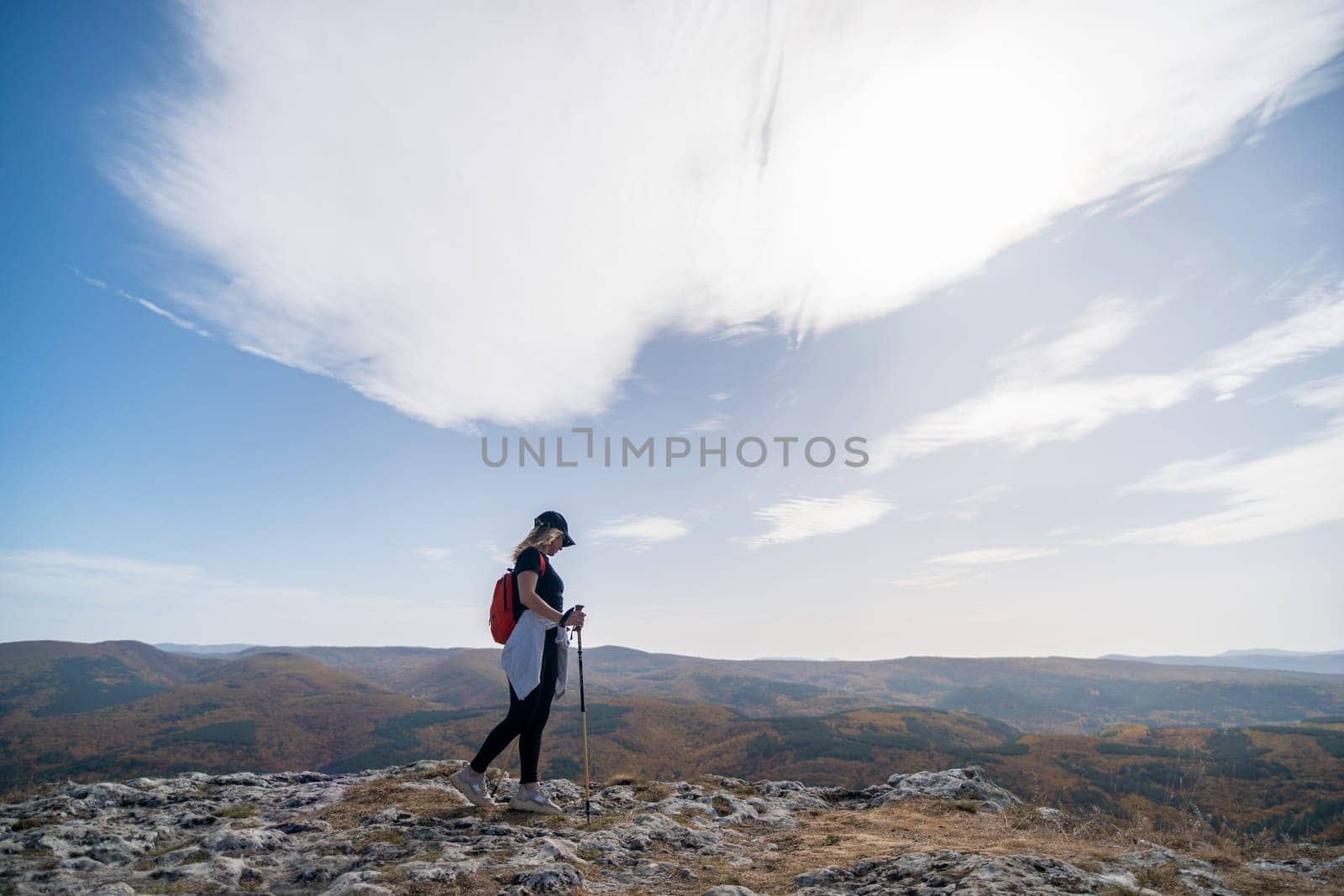 woman on mountain peak looking in beautiful mountain valley in autumn. Landscape with sporty young woman, blu sky in fall. Hiking. Nature.