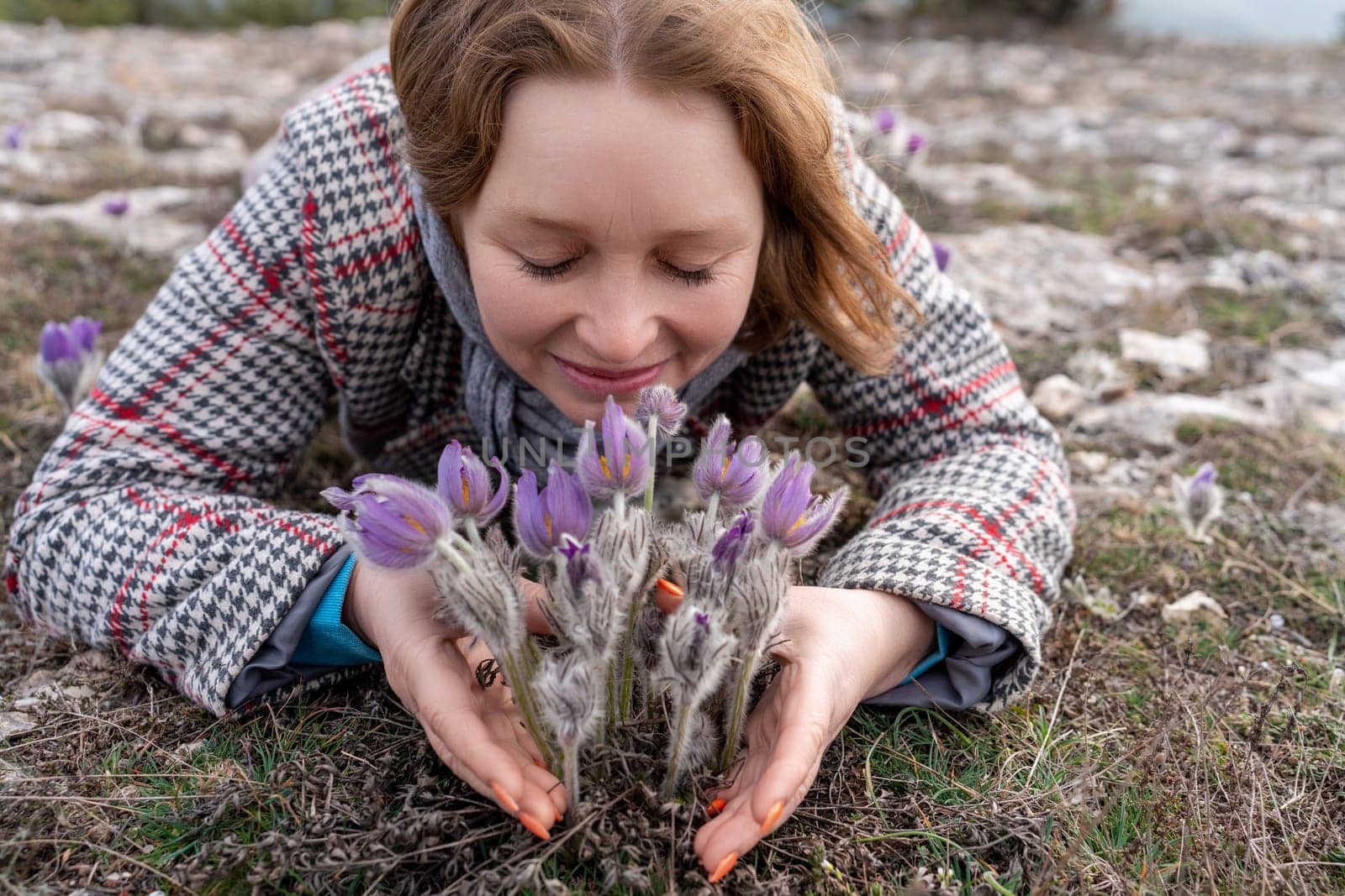 Dream grass woman spring flower. Woman lies on the ground and hugs flowers pasqueflower or Pulsatilla Grandis flowers by Matiunina