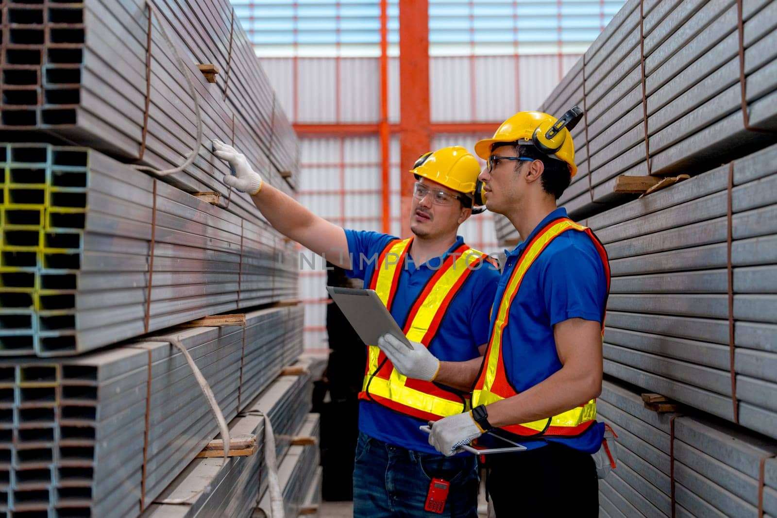 Caucasian factory workers hold tablet touch and check the product of metal pipe in factory workplace area, good management industry factory concept.