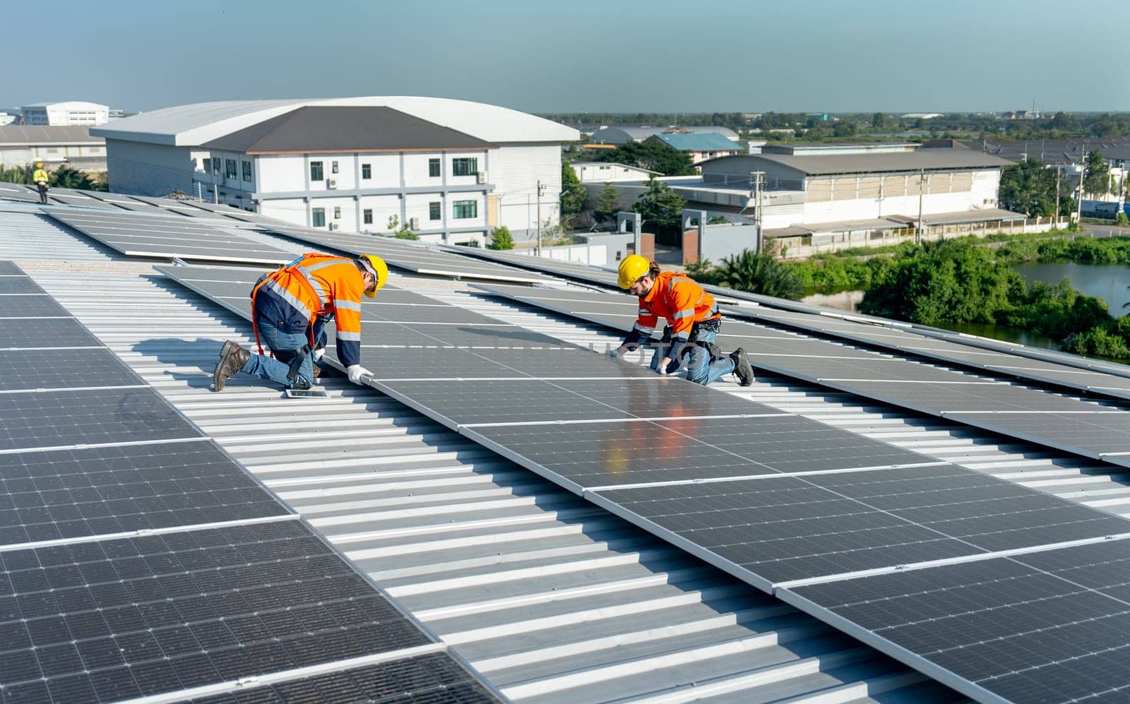 Wide shot of two Caucasian technician workers work with install the solar cell panels on rooftop of factory or the building. Green and sustainable energy concept.