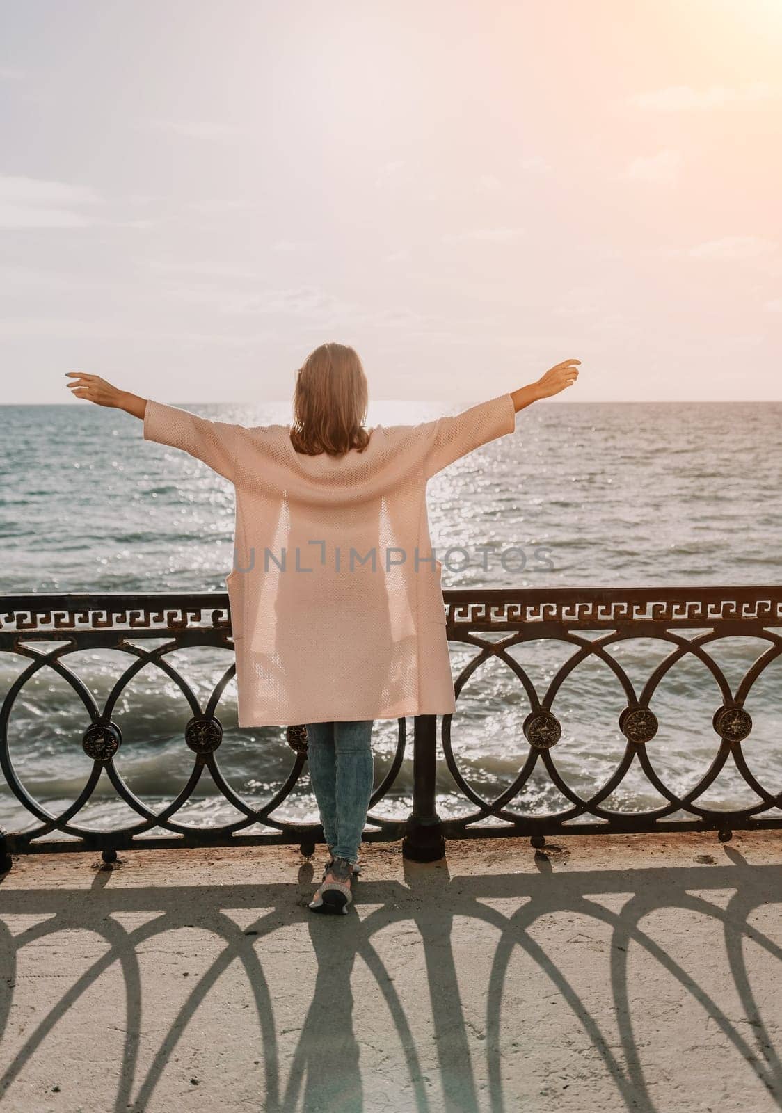 Woman summer travel sea. Happy tourist enjoy taking picture outdoors for memories. Carefree woman traveler posing on beach at sea on sunset, sharing travel adventure journey. Holiday vacation concept. by panophotograph