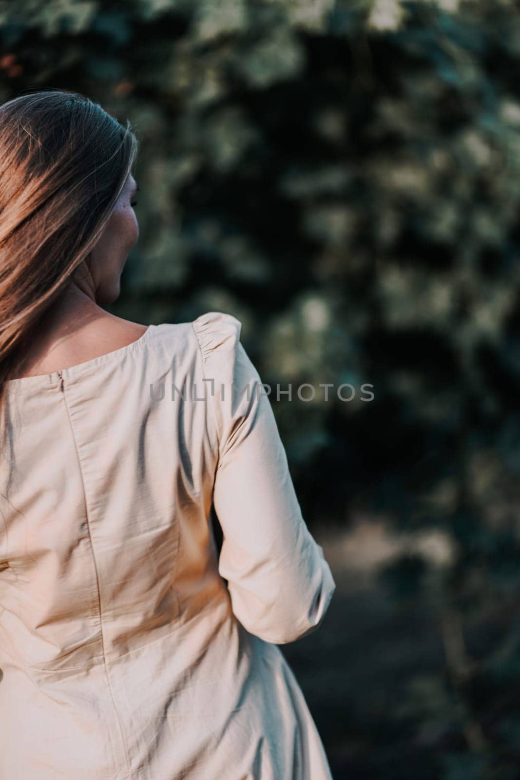 Woman with straw hat stands in front of vineyard. She is wearing a light dress and posing for a photo. Travel concept to different countries by Matiunina