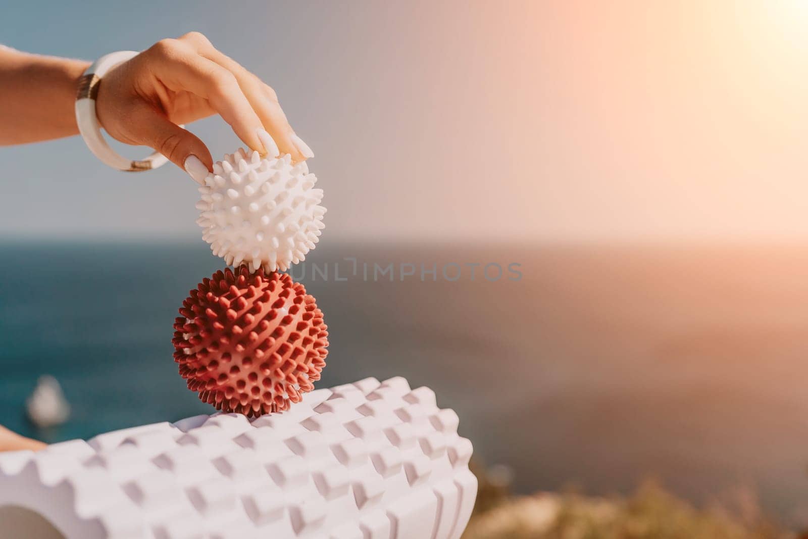 Woman sea pilates. Sporty happy middle aged woman practicing fitness on yoga mat with massage balls and roller near sea, smiling active female outside, enjoying healthy lifestyle, harmony by panophotograph