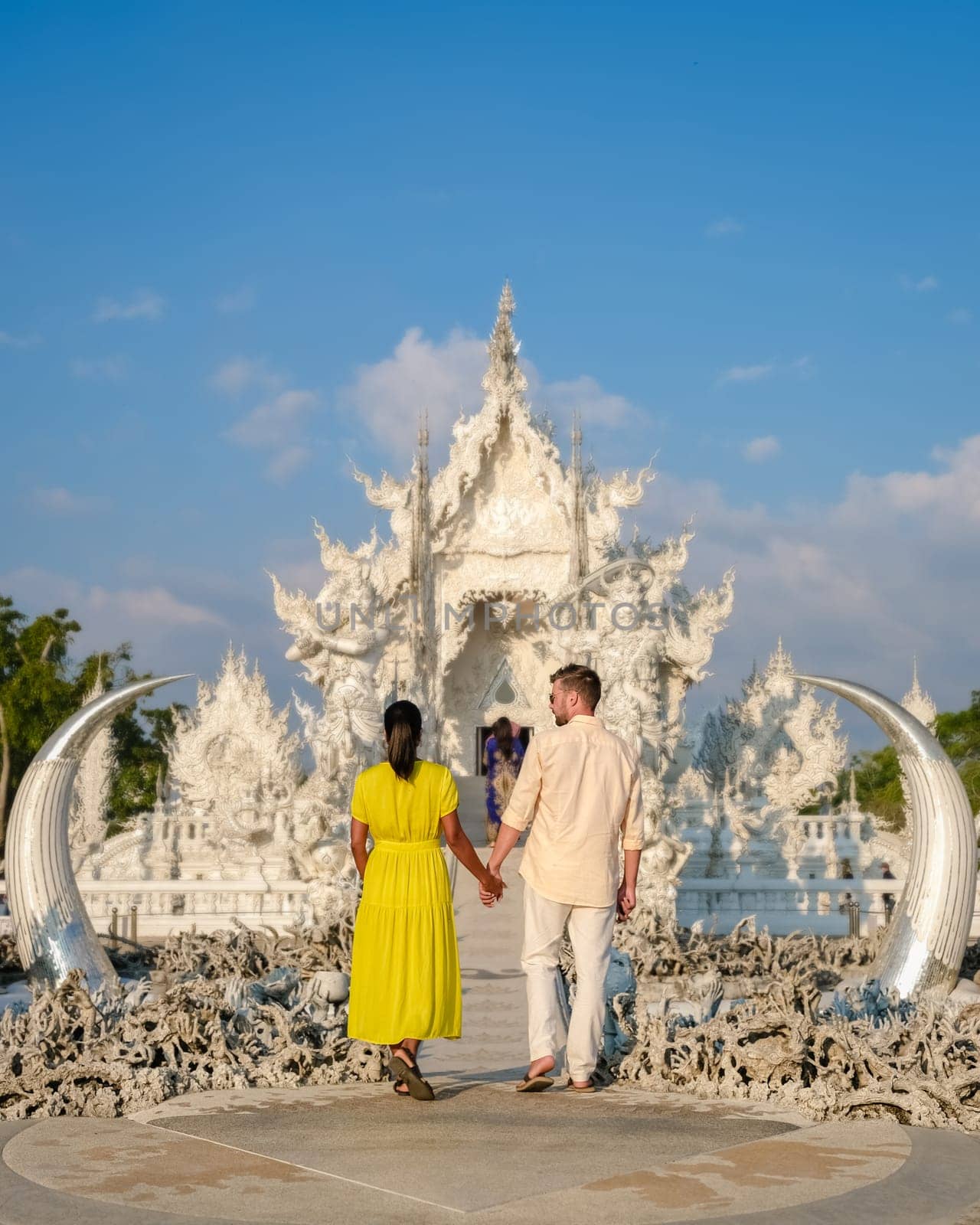 White Temple Chiang Rai Thailand,a diverse couple of men and women visit Wat Rong Khun temple at sunset, Northern Thailand.