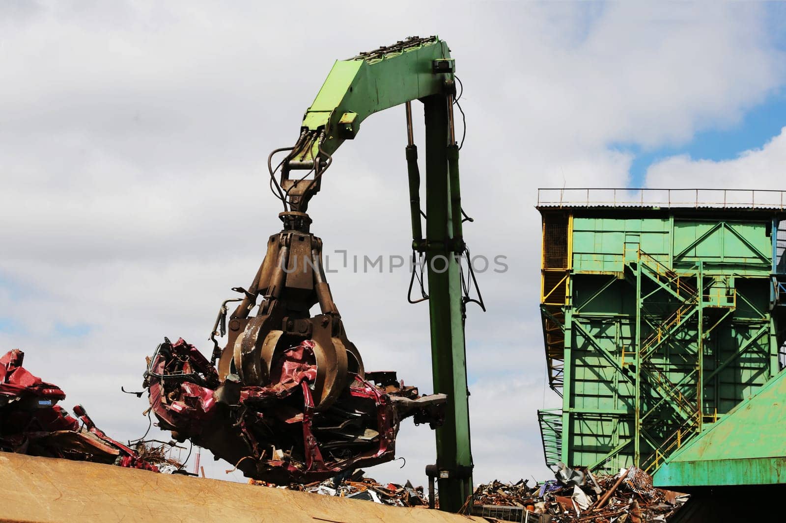 A jaw crane puts scrap metal into a crusher for raw materials. Crane against the sky.