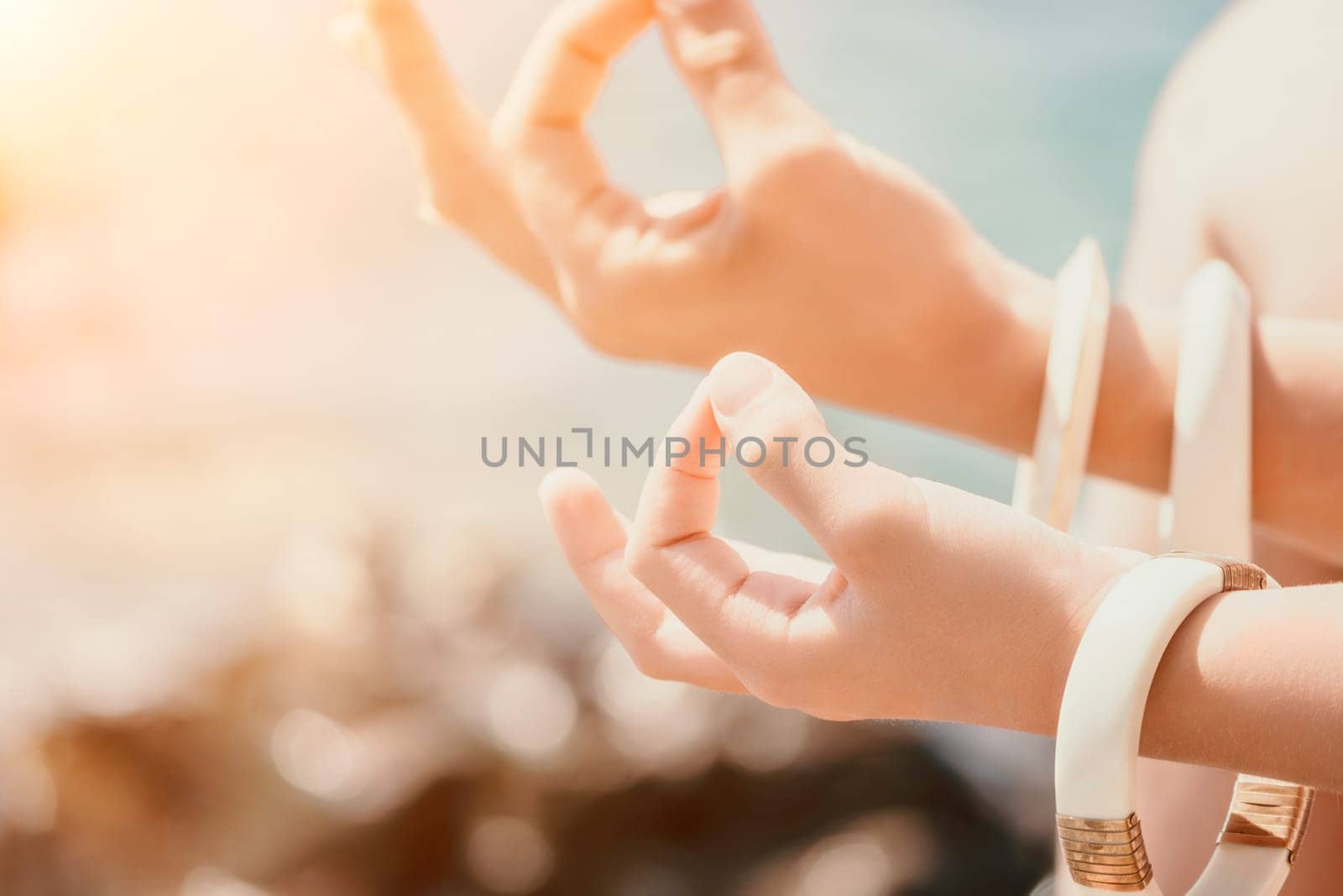 Close up Yoga Hand Gesture of Woman Doing an Outdoor meditation. Blurred sea background. Woman on yoga mat in beach meditation, mental health training or mind wellness by ocean, sea by panophotograph