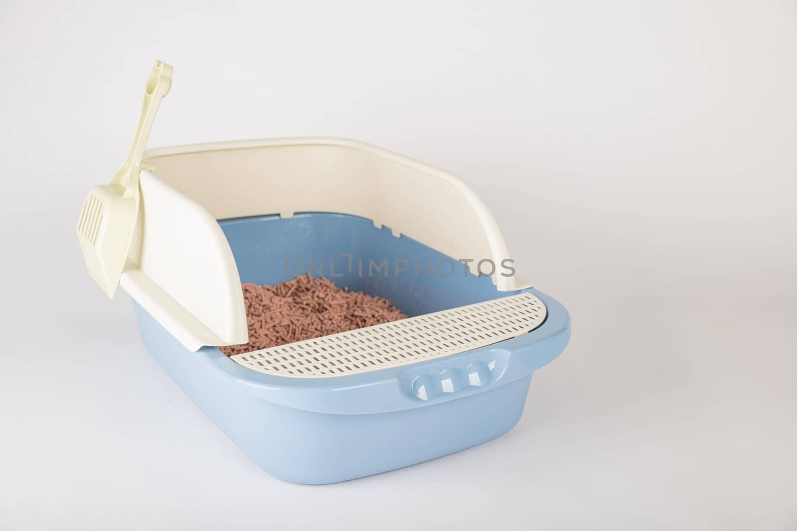 Ensure the hygiene and cleanliness of your cat's crate with an isolated plastic cat litter toilet tray and scoop on a white background.