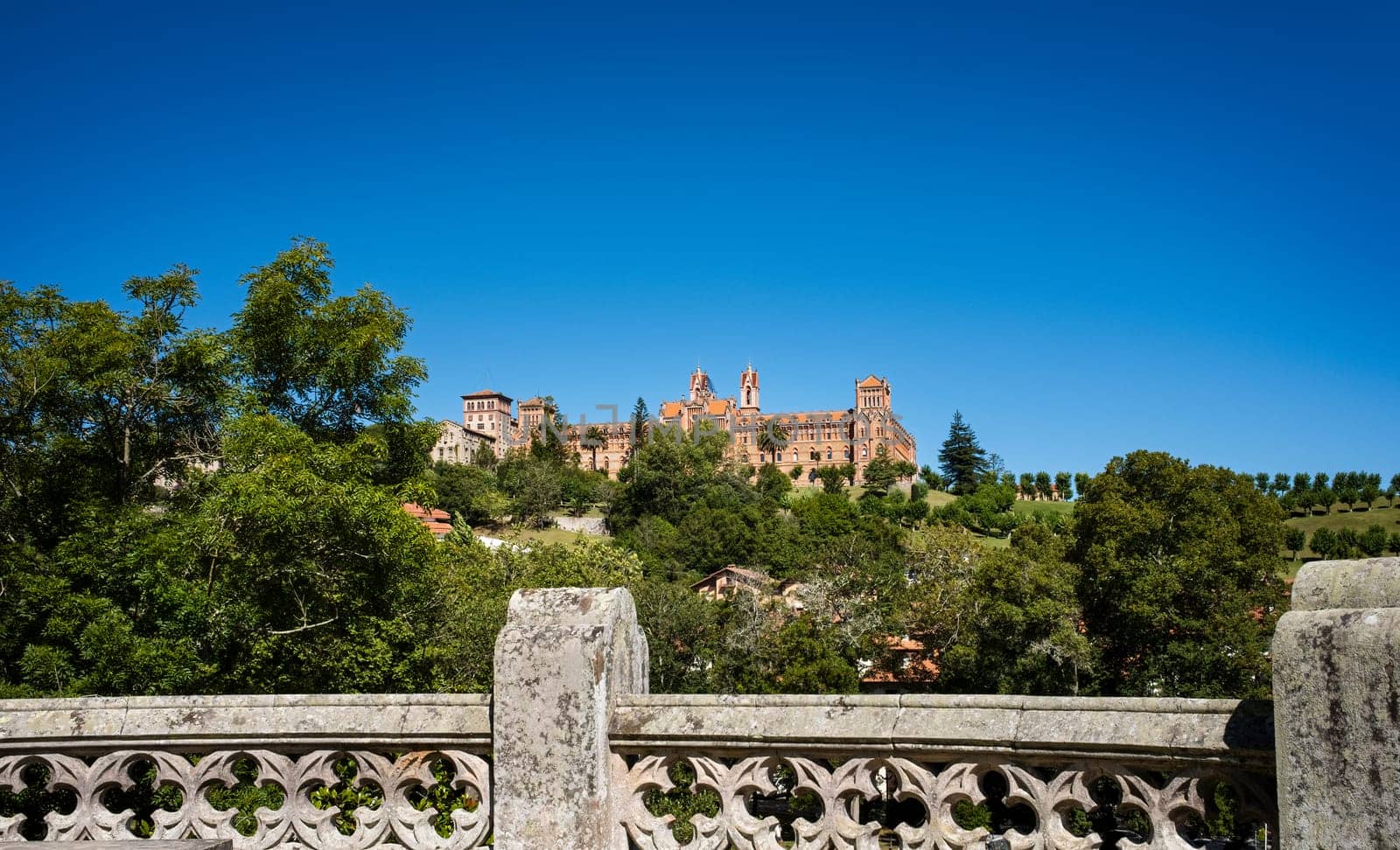 View of the Pontifical University of Comillas from the palace of Sobrellano, with clear blue skies.