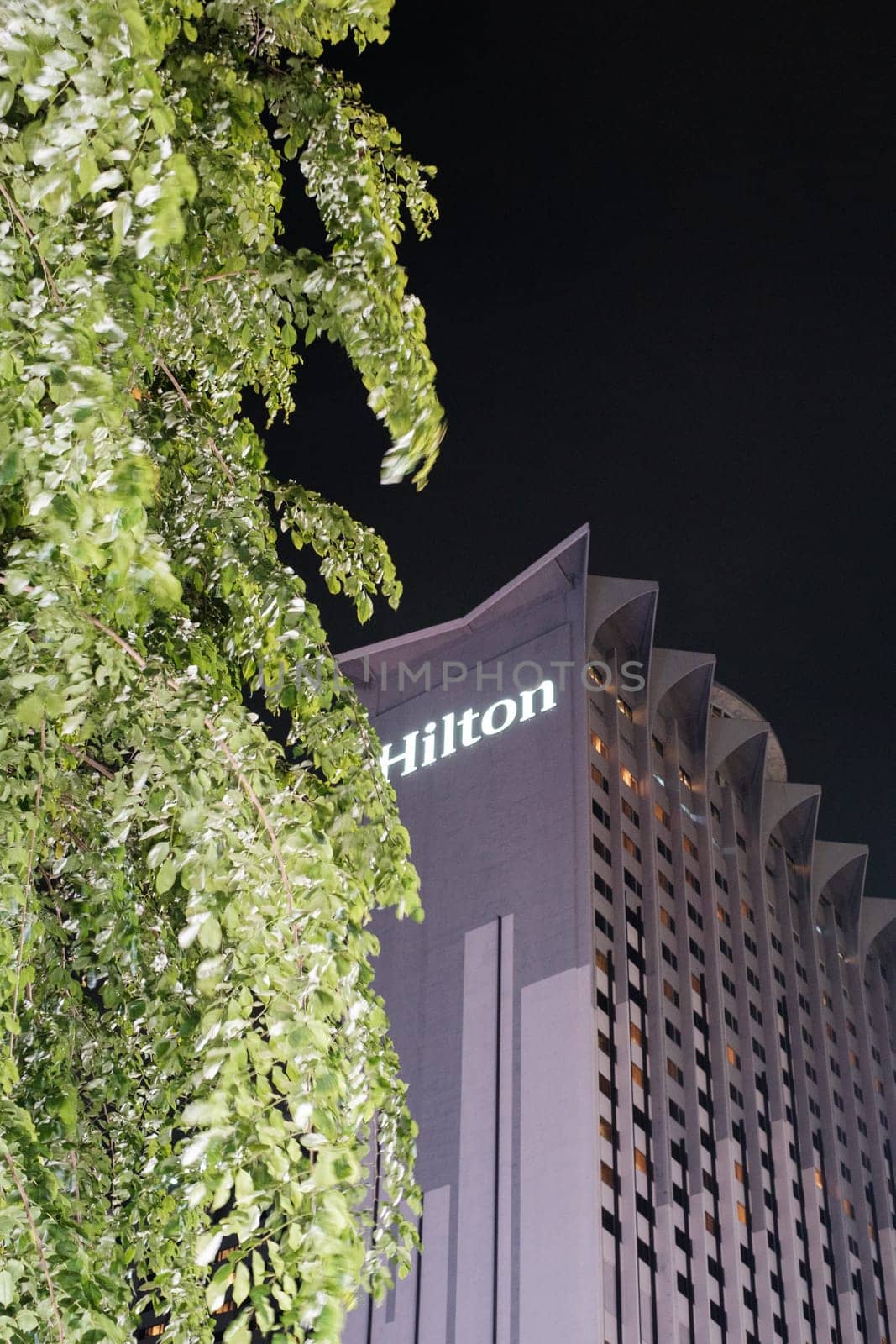 Singapore - August 24 2023: Hilton Hotel Illumination Amidst Foliage