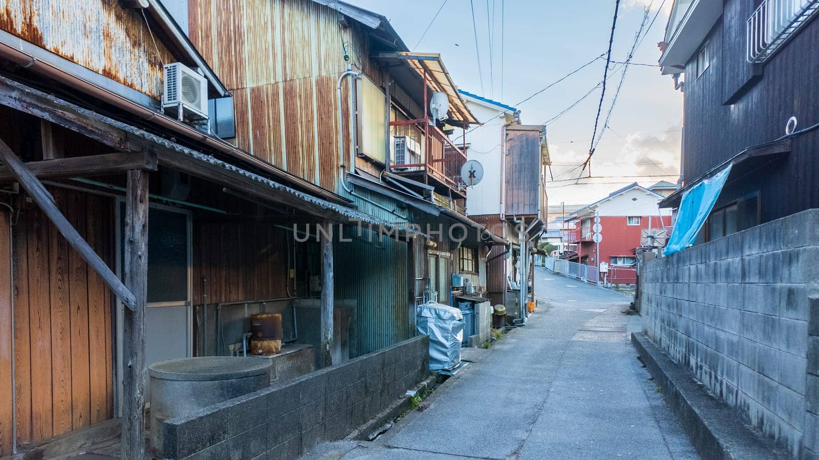 Narrow road between old houses in small town Japan by Osaze